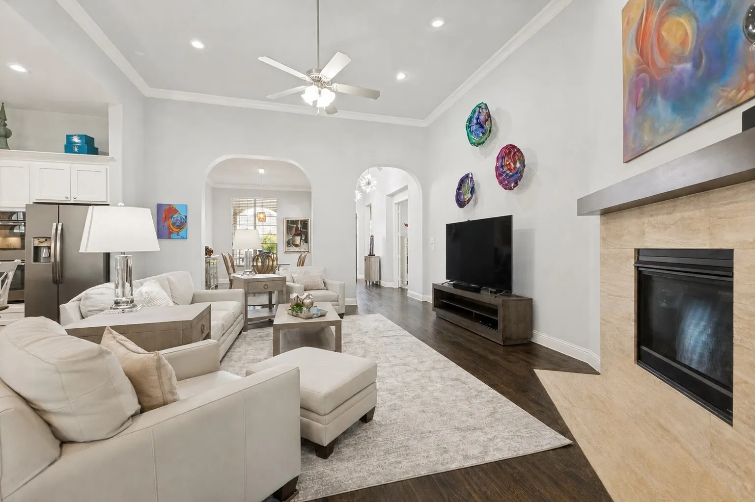 Arched doorways, recessed lighting, and a ceiling fan enhance this large space that overlooks the kitchen.