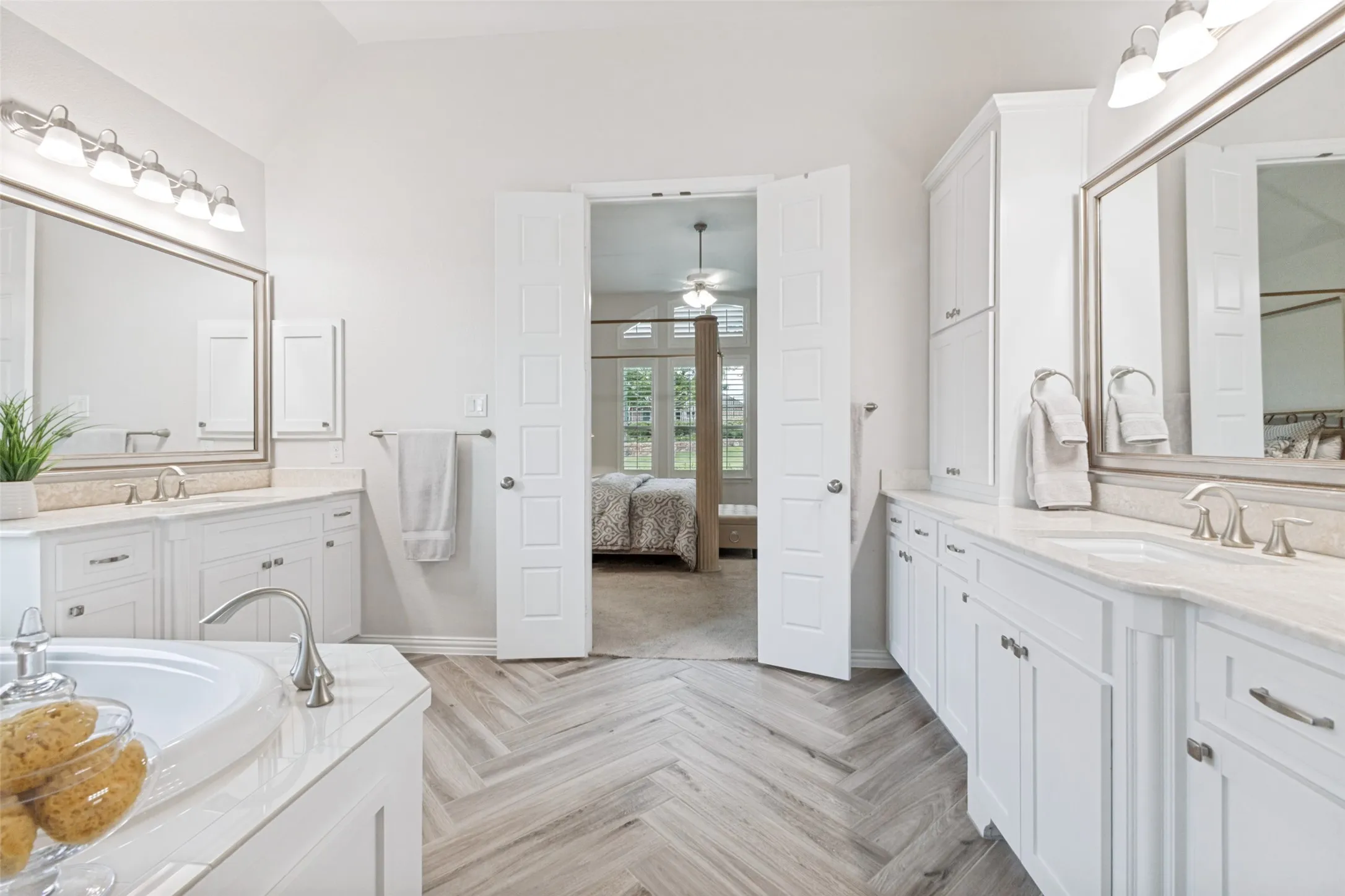 Dual vanity with white cabinetry and herringbone tile floors.