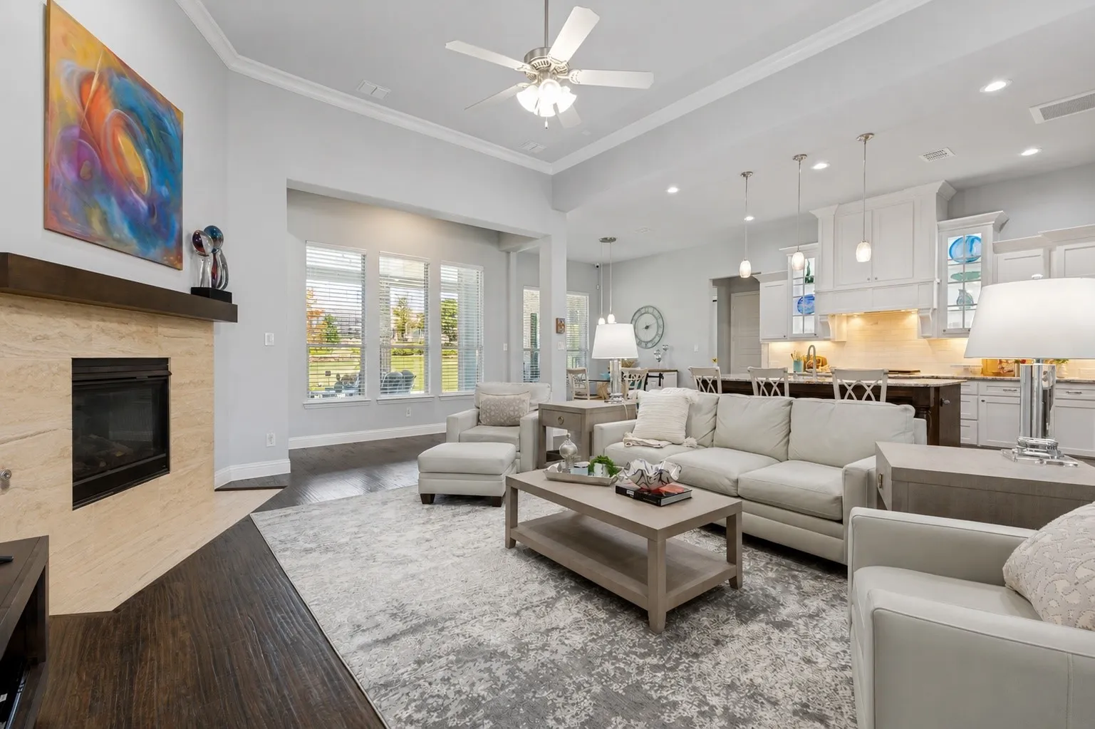 Open-concept living area with hard wood flooring, a contemporary fireplace with tile surround, and abundant natural light from multiple windows.