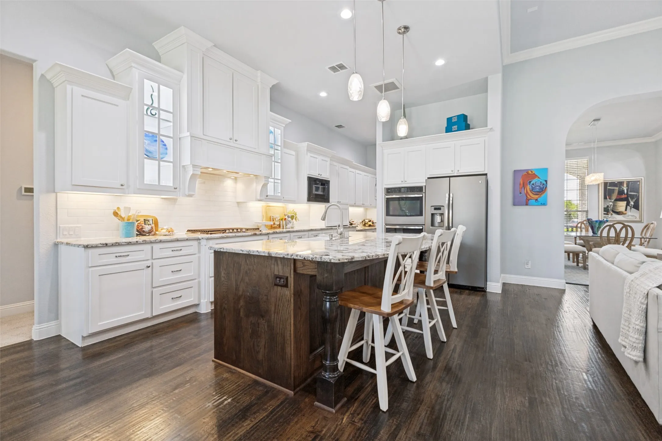 Modern white kitchen with cabinetry to the ceiling, lighted display cabinets, large island with granite counters, coffee bar area and custom slide out cabinets.