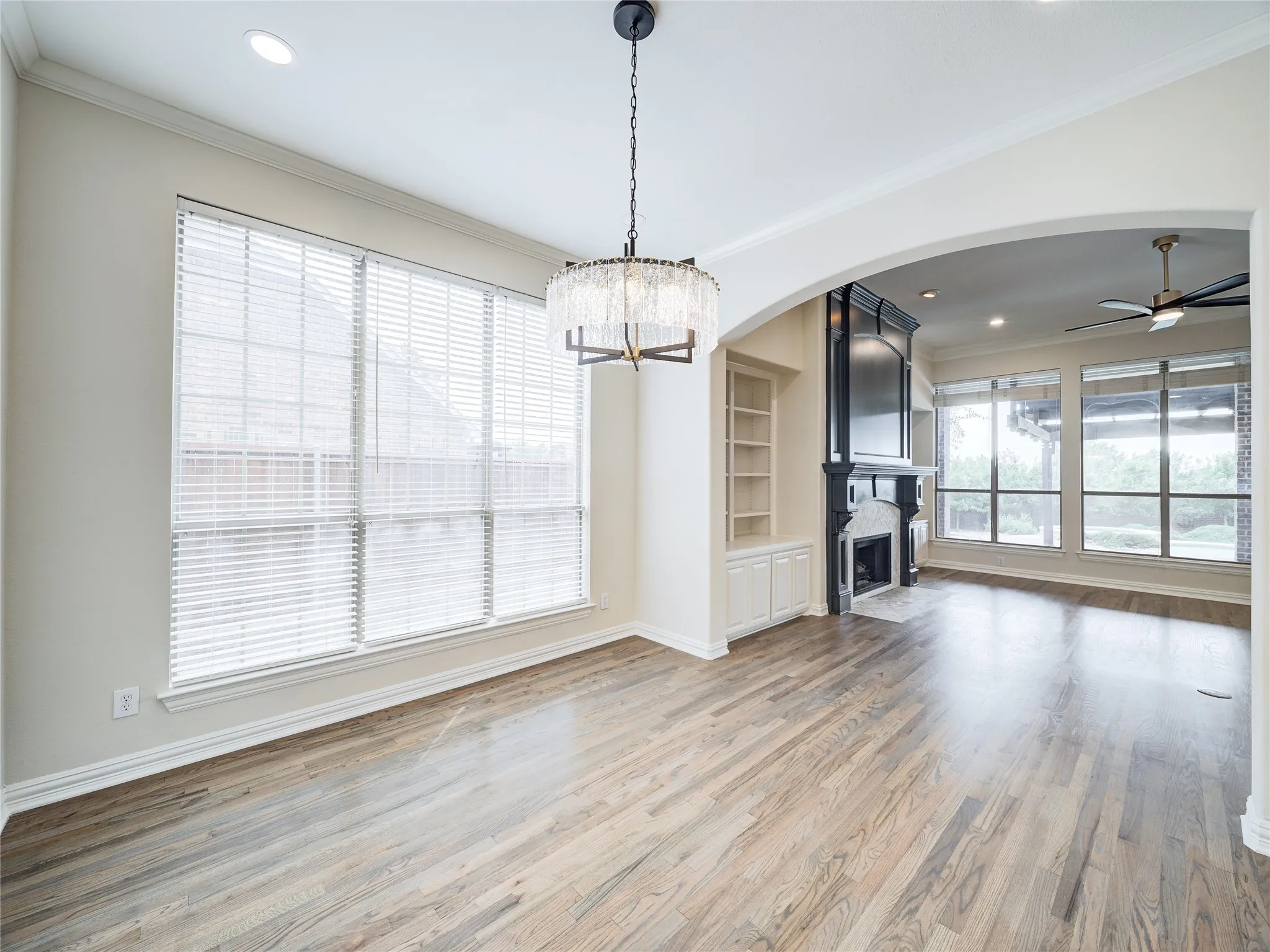 Spacious interior featuring wood-finish flooring, a contemporary chandelier, recessed lighting, and large windows with blinds