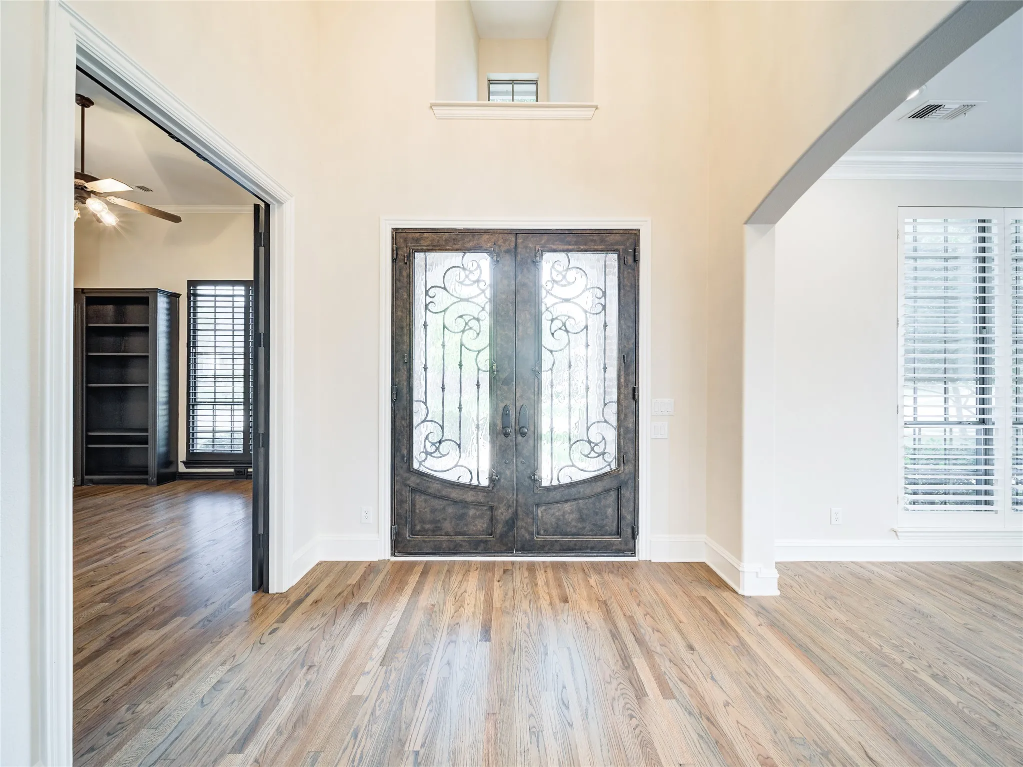 Grand entry featuring double wrought iron and glass doors with a decorative transom window