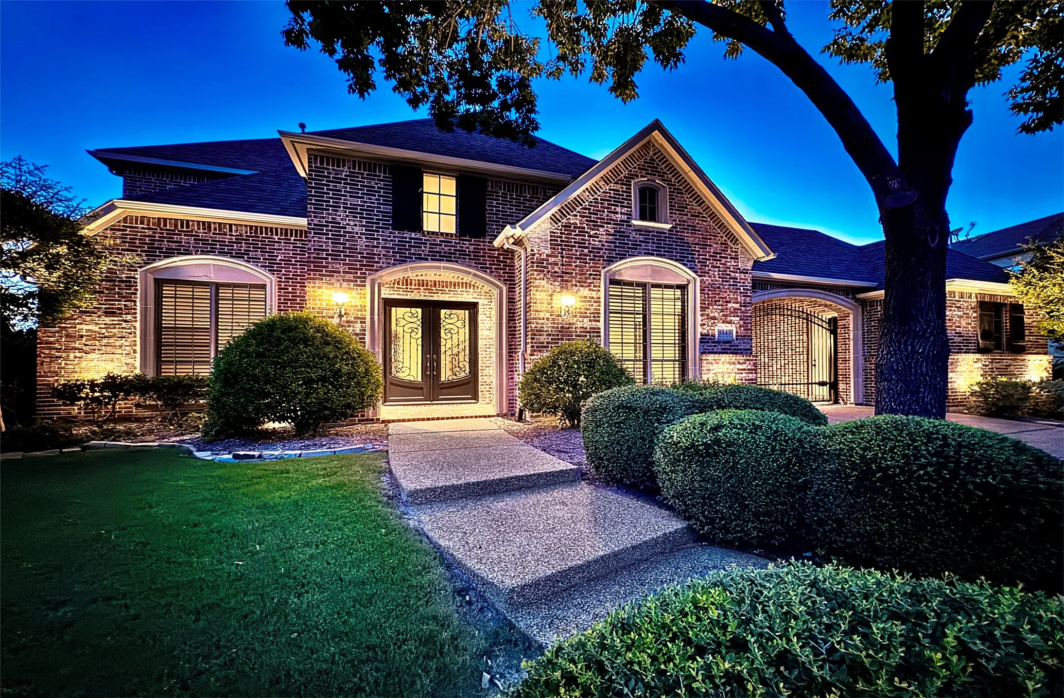 Brick exterior featuring a gabled entryway, arched windows, and decorative double front doors