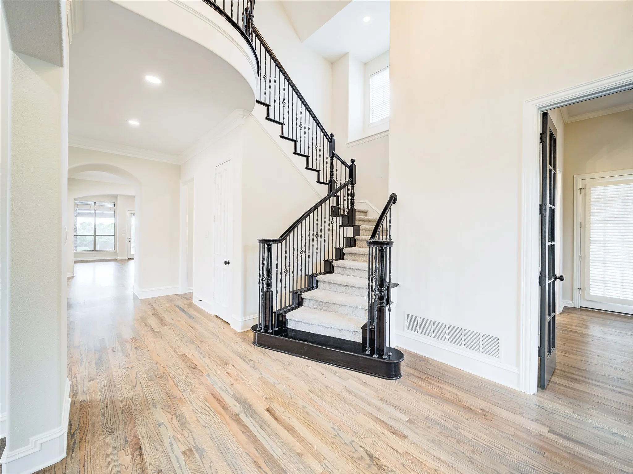 Grand entry foyer featuring a sweeping staircase with a dark wood handrail and wrought iron balusters