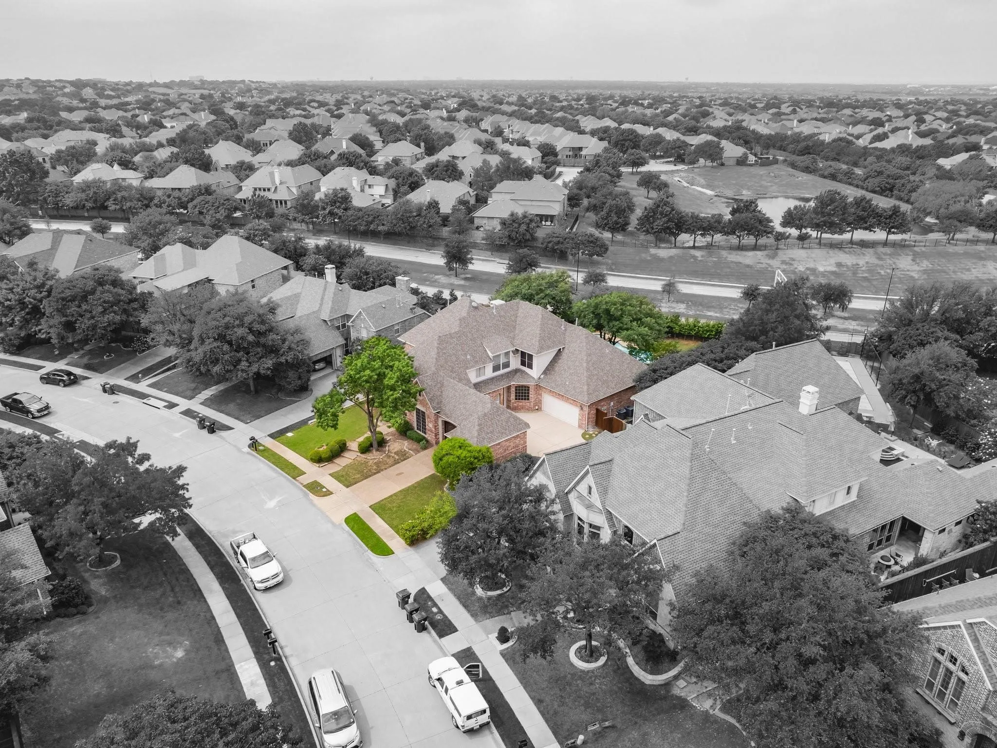 Brick exterior residence with a multi-gabled roofline, featuring an attached garage and a manicured front lawn with mature landscaping