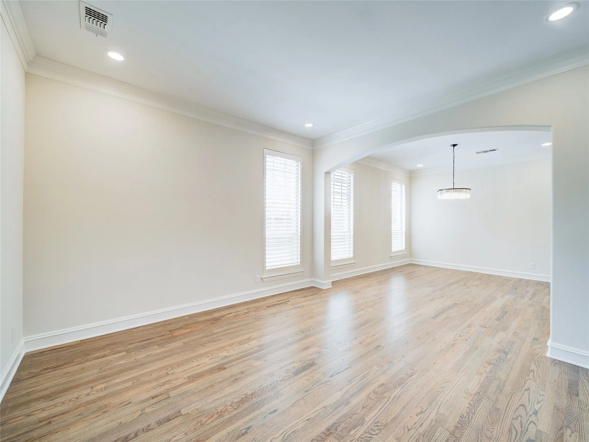 Expansive room featuring wood-finish flooring, recessed lighting, and crown molding