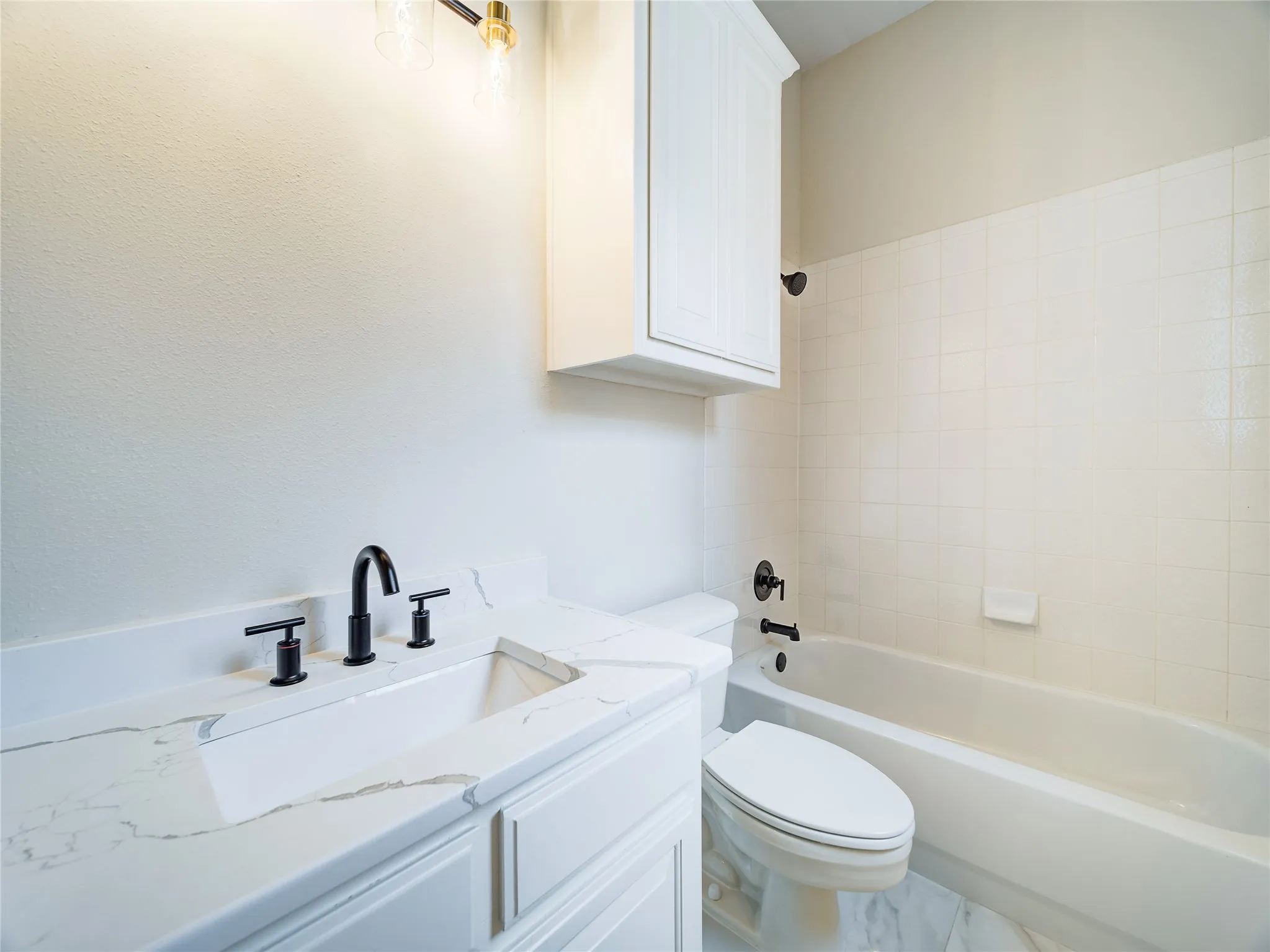 Bathroom featuring a white vanity with a rectangular undermount sink, quartz countertop, and matte black faucet