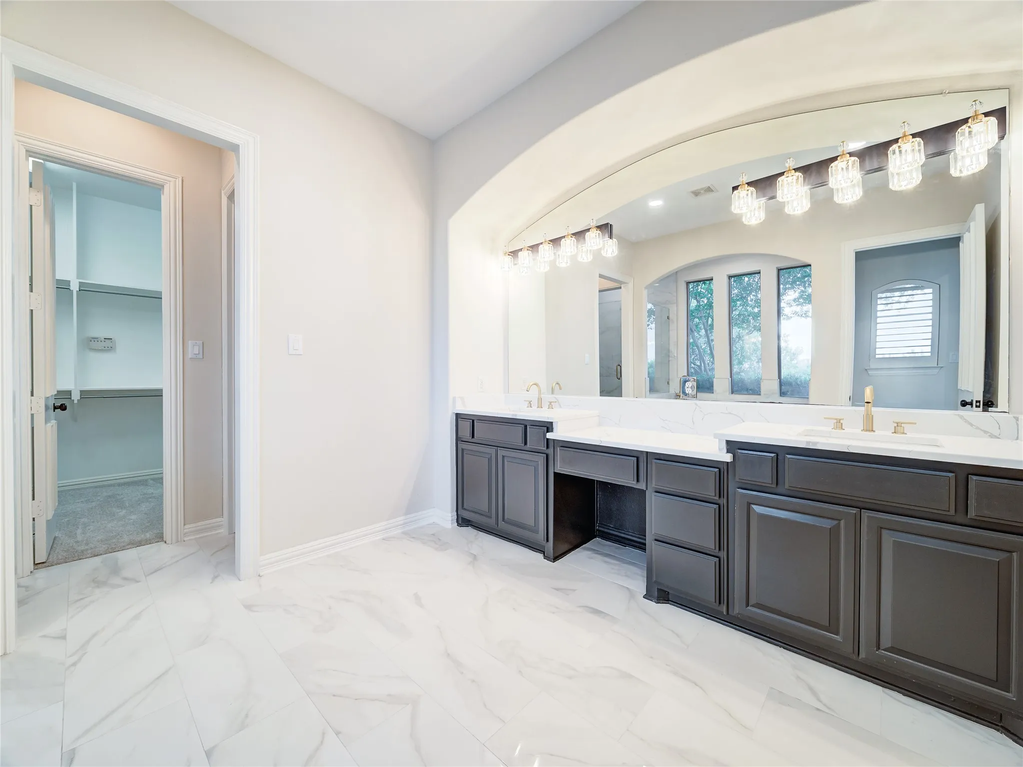 Dual vanity with dark wood cabinetry, white countertops, and gold-finish fixtures