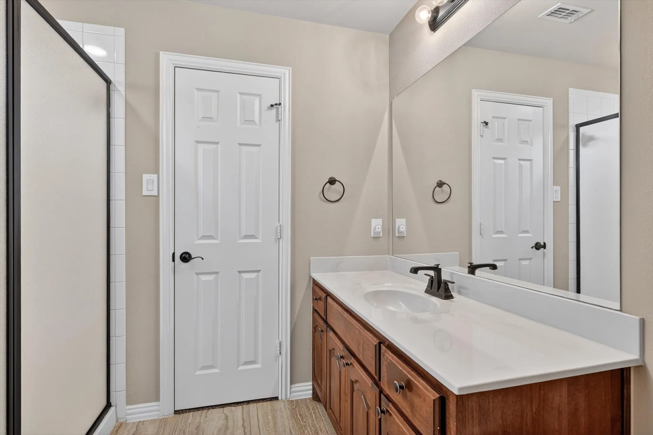 Bathroom vanity featuring a light-colored countertop, dark wood-finish cabinetry, and a single basin sink with a dark-finish faucet