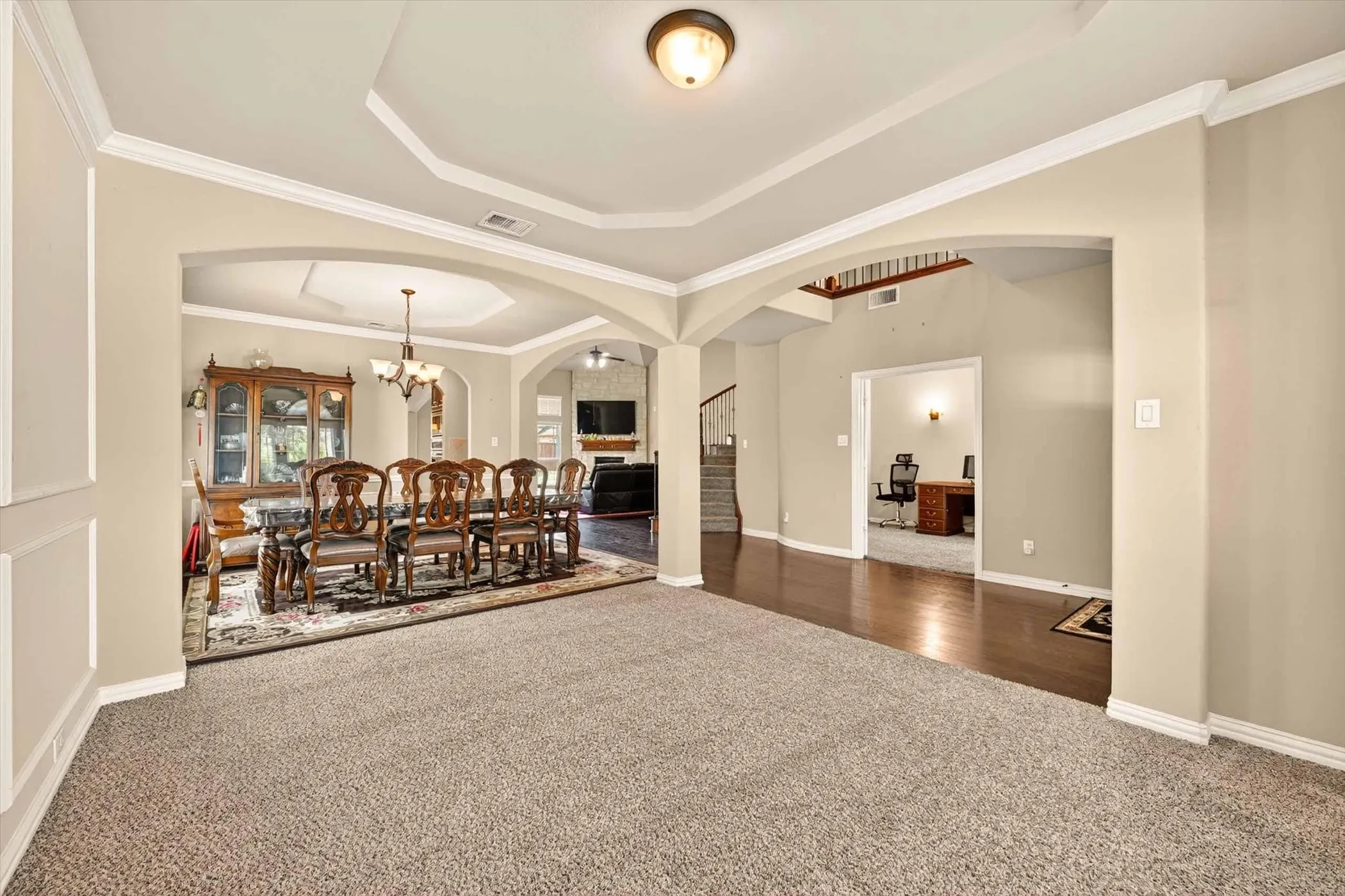 Formal dining area featuring an arched entryway, tray ceiling, and decorative chandelier