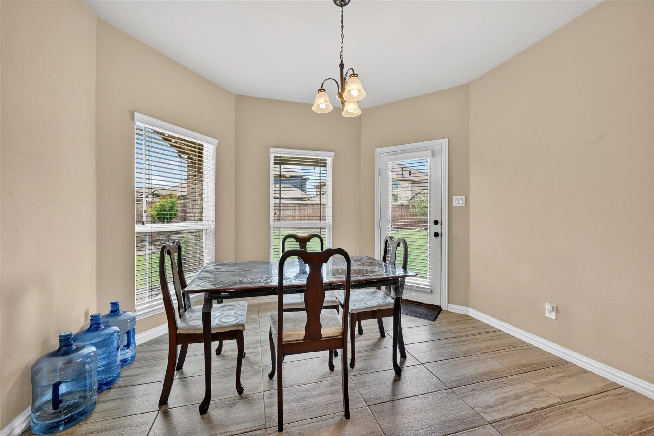 Dining area featuring three windows with blinds, a glass-paned exterior door, and tile flooring