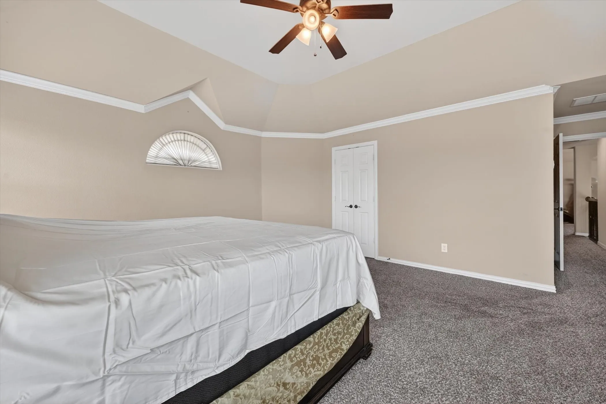 Spacious bedroom with vaulted ceilings, a ceiling fan, and crown molding