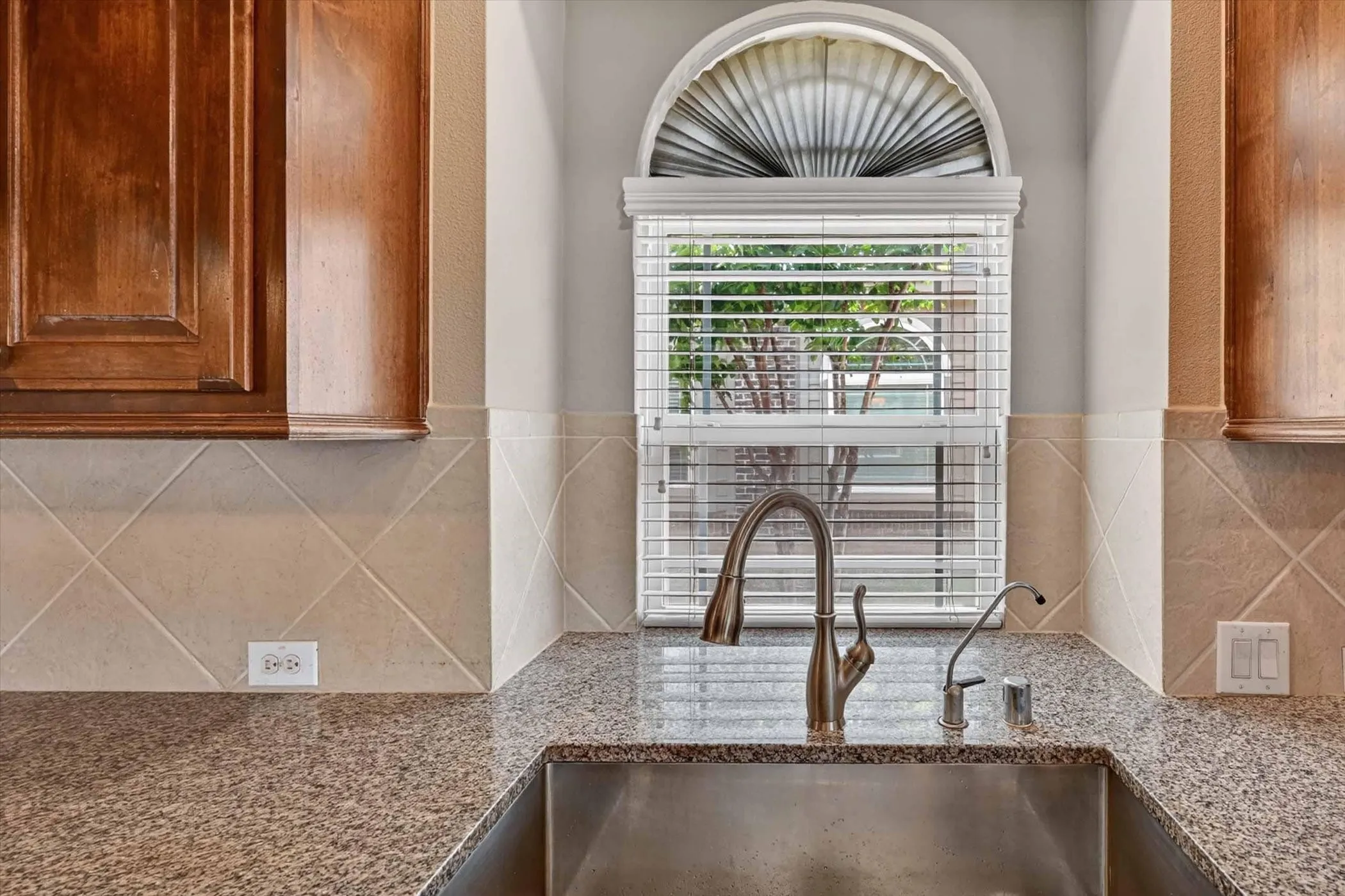 Kitchen sink area featuring a stainless steel undermount sink, granite countertops, and a brushed nickel gooseneck faucet