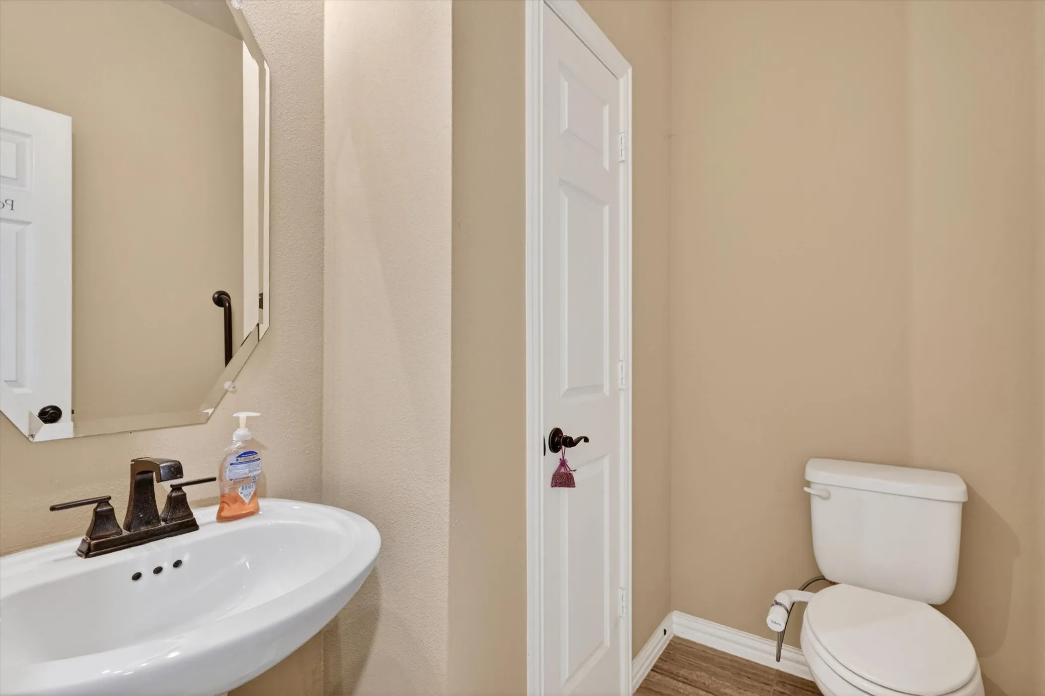 Pedestal sink with bronze-finish faucet, framed by an octagonal mirror