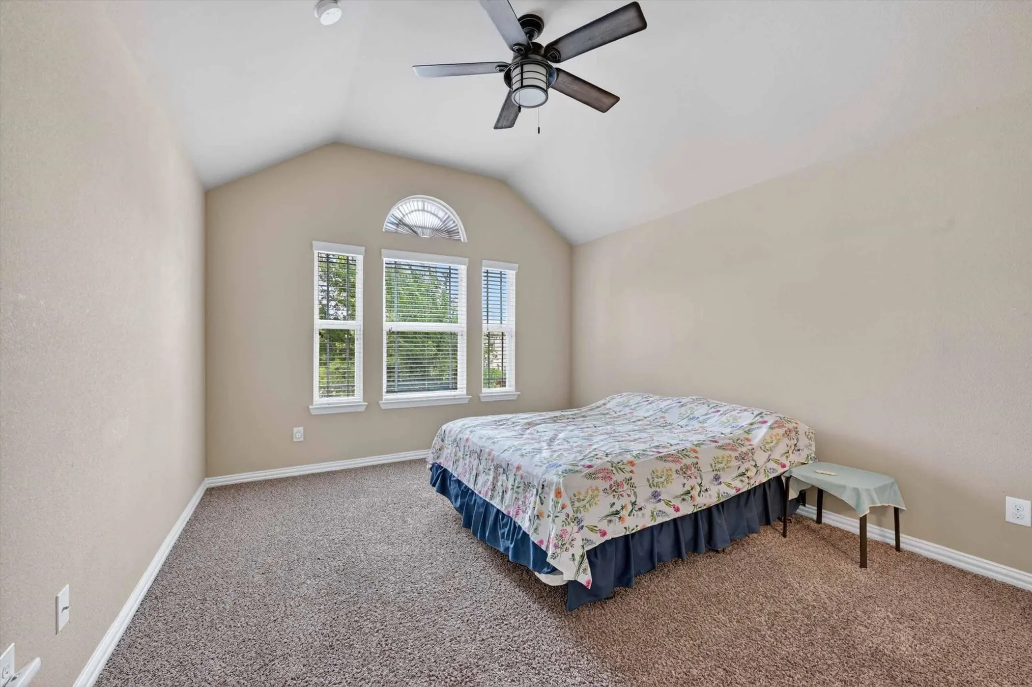 Vaulted ceiling with an integrated ceiling fan, carpeted flooring, and multiple windows with blinds