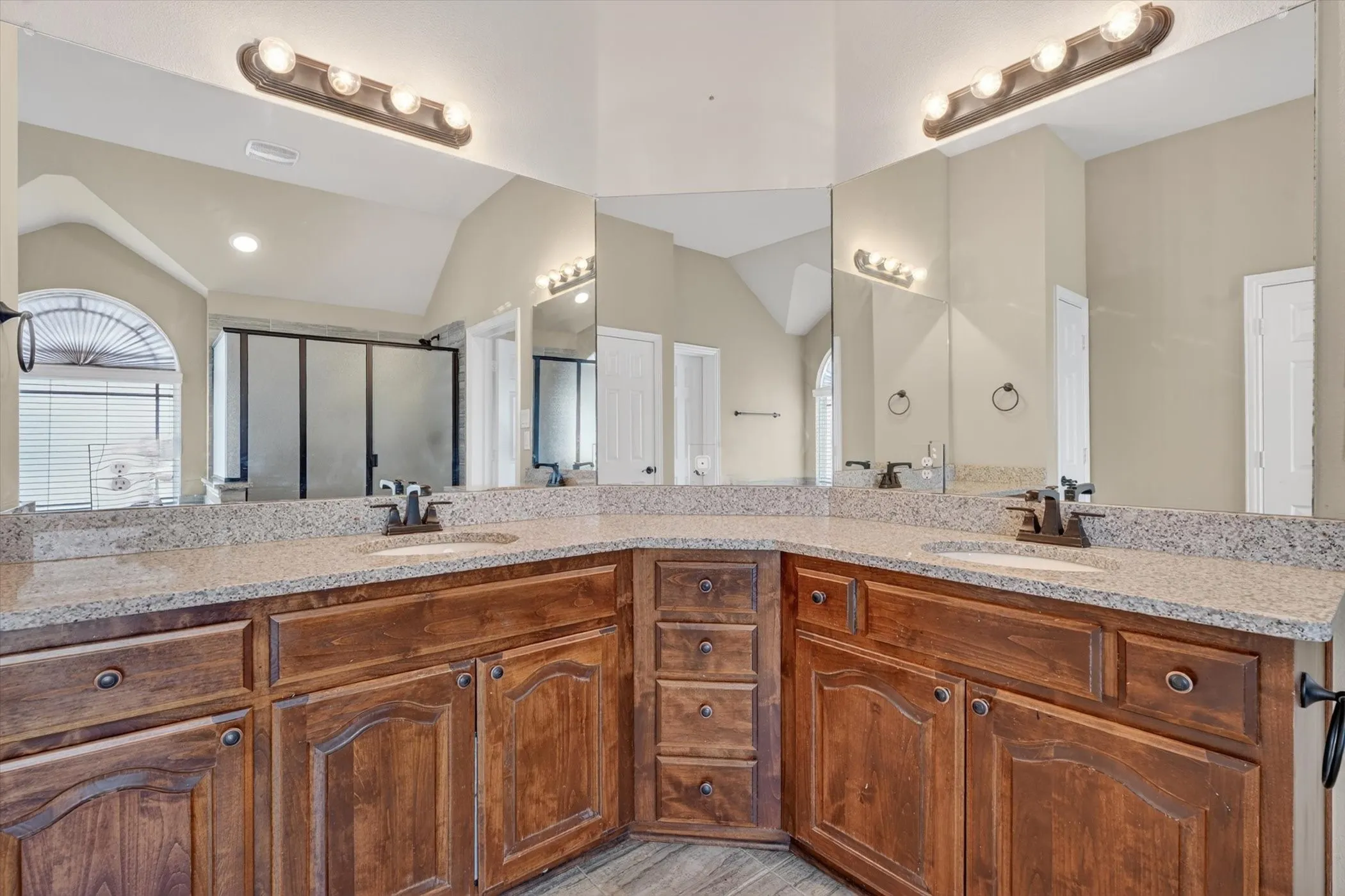 Dual wood-finish vanities with granite-style countertops and integrated sinks