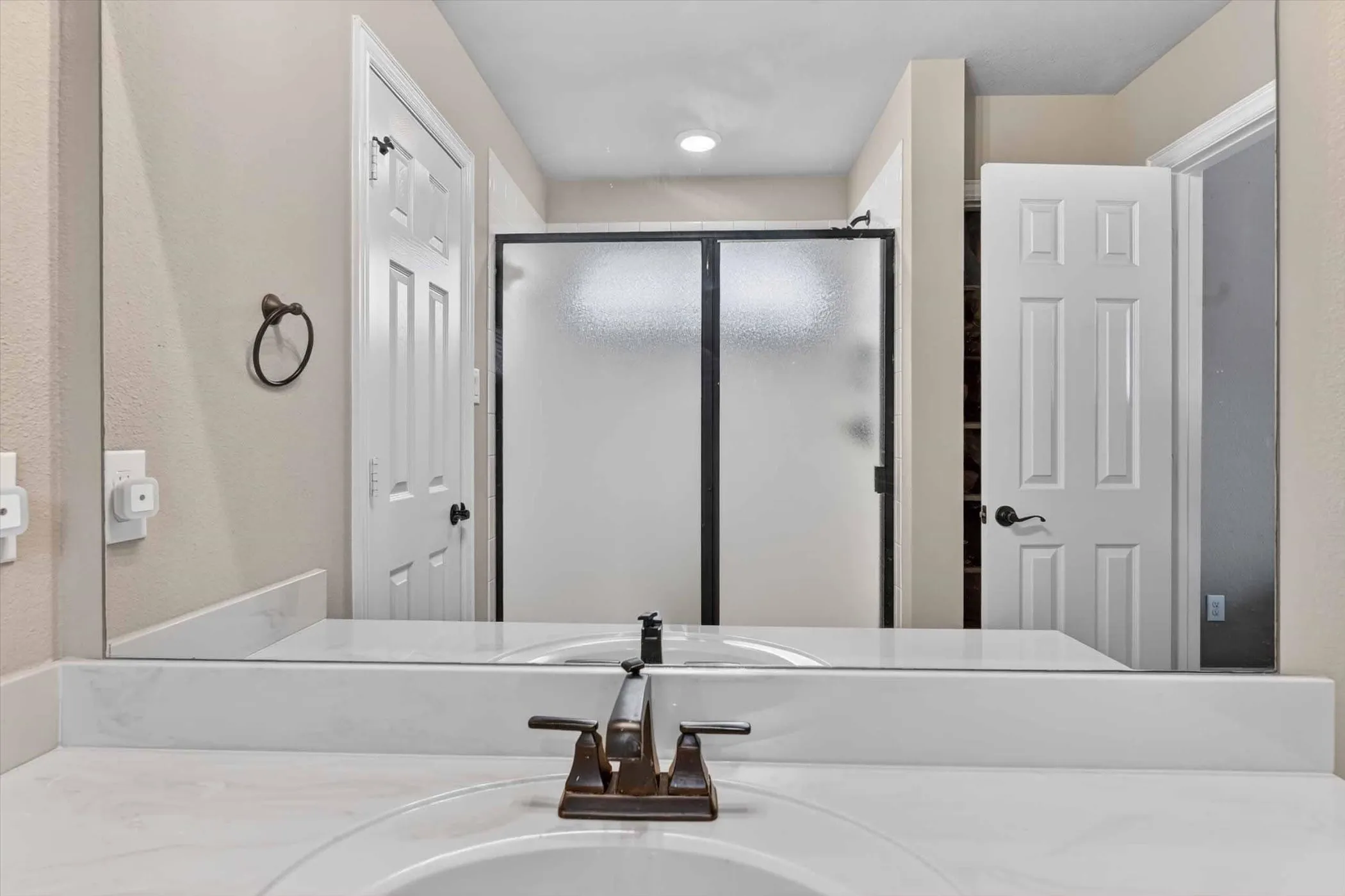Double vanity with integrated sinks and white countertops, featuring bronze-finish hardware