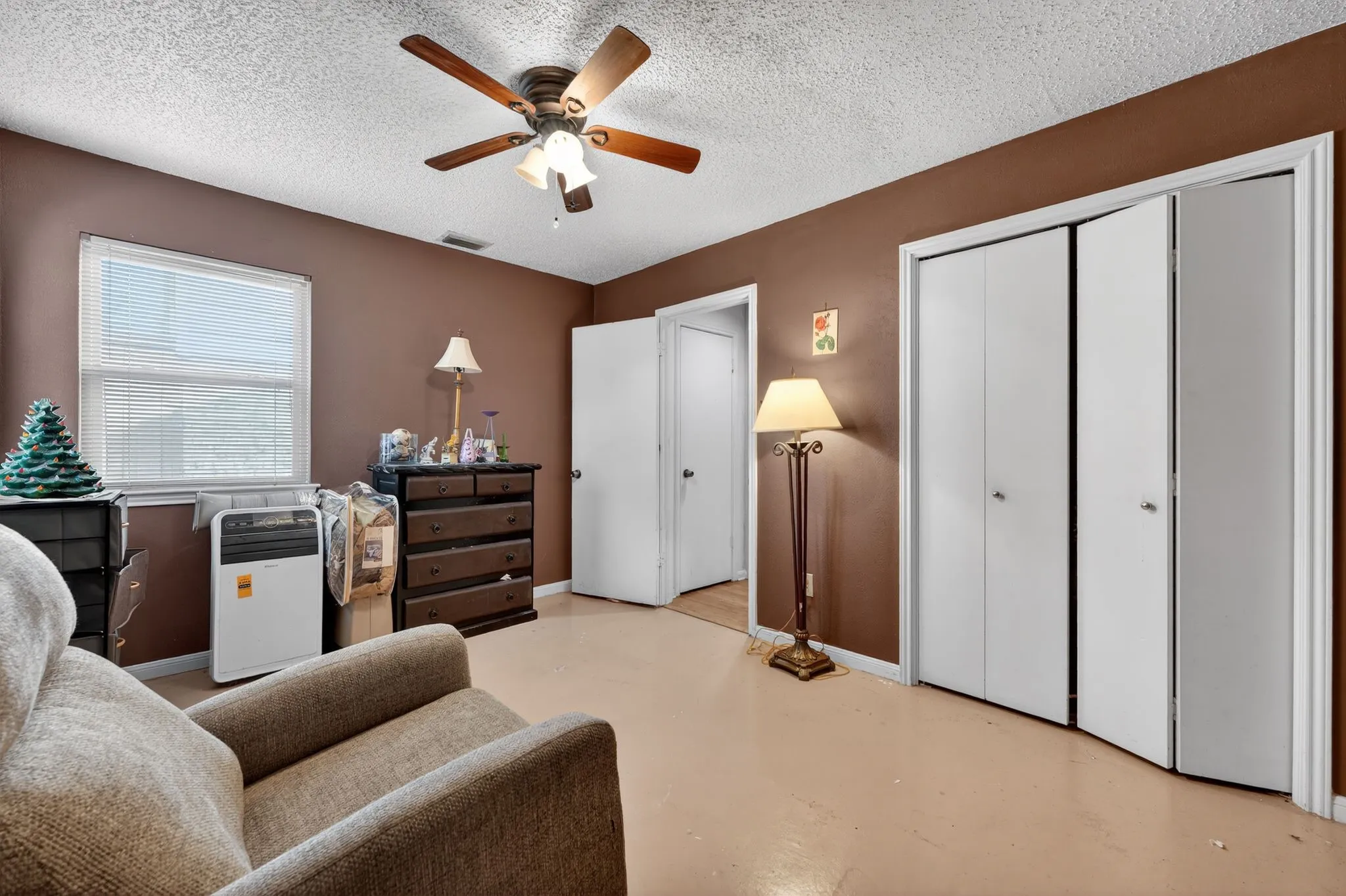 Room featuring a ceiling fan with light, single window with horizontal blinds, and bi-fold closet doors