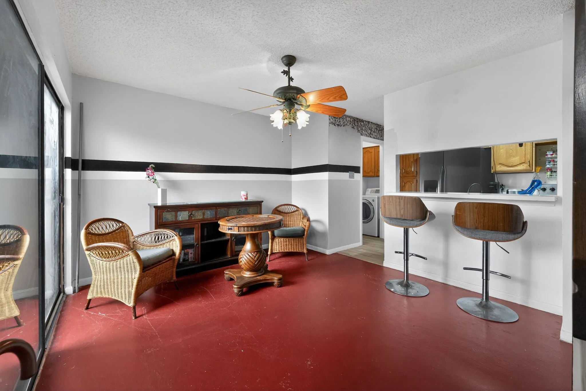 Open-concept living area featuring red flooring and a ceiling fan