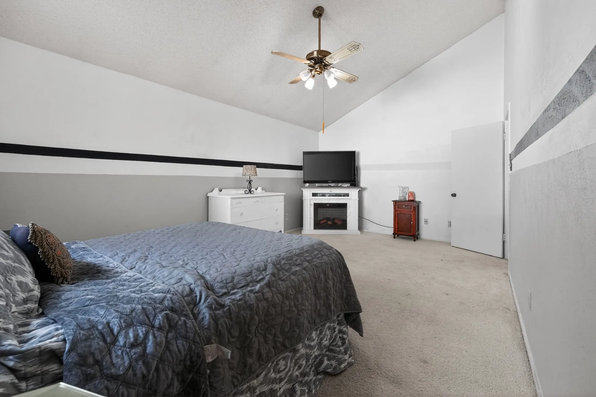 Carpeted room featuring a sloped ceiling and a ceiling fan