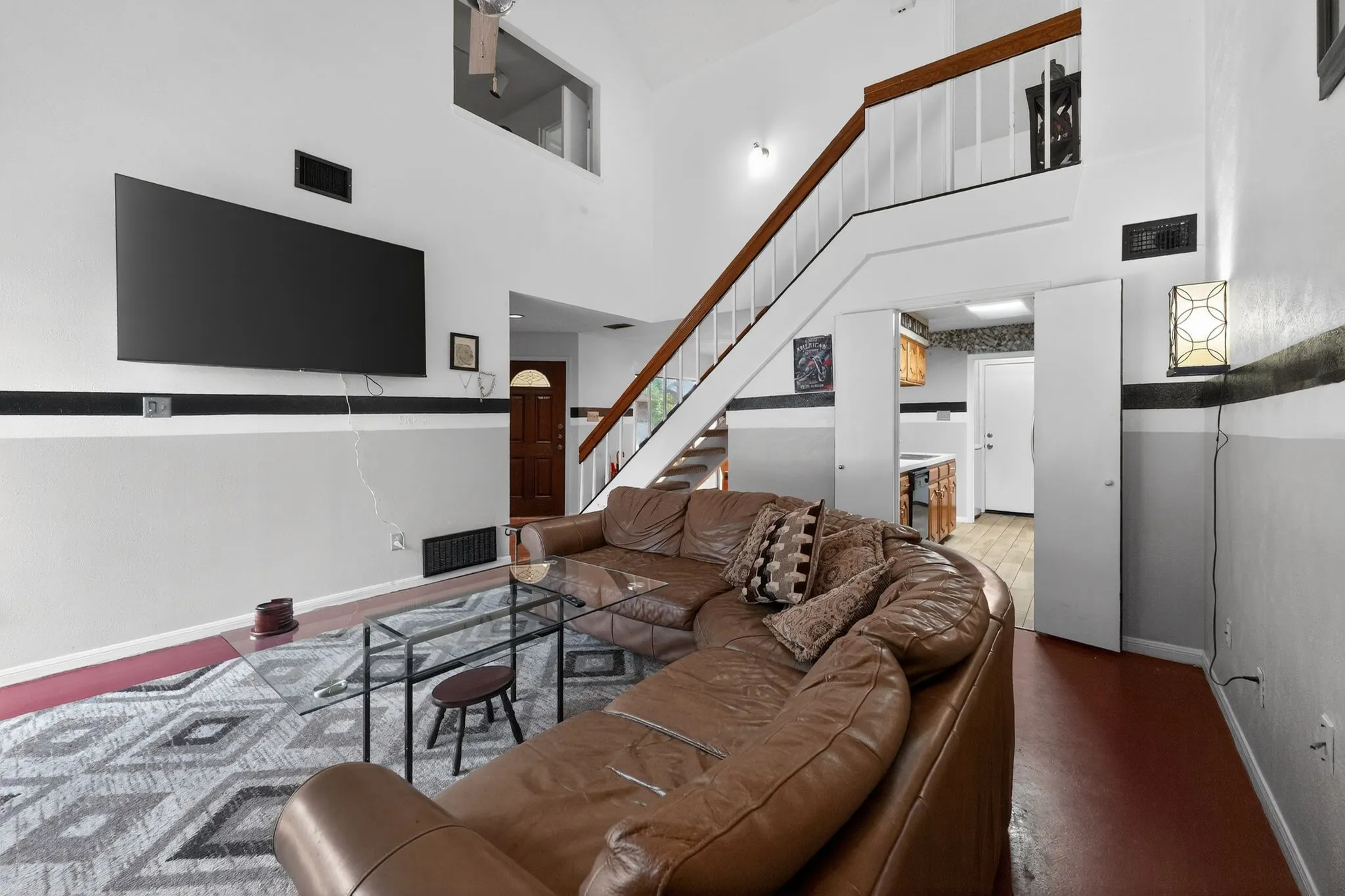 Two-story living area with high ceilings and a prominent staircase featuring wood handrails and white balusters