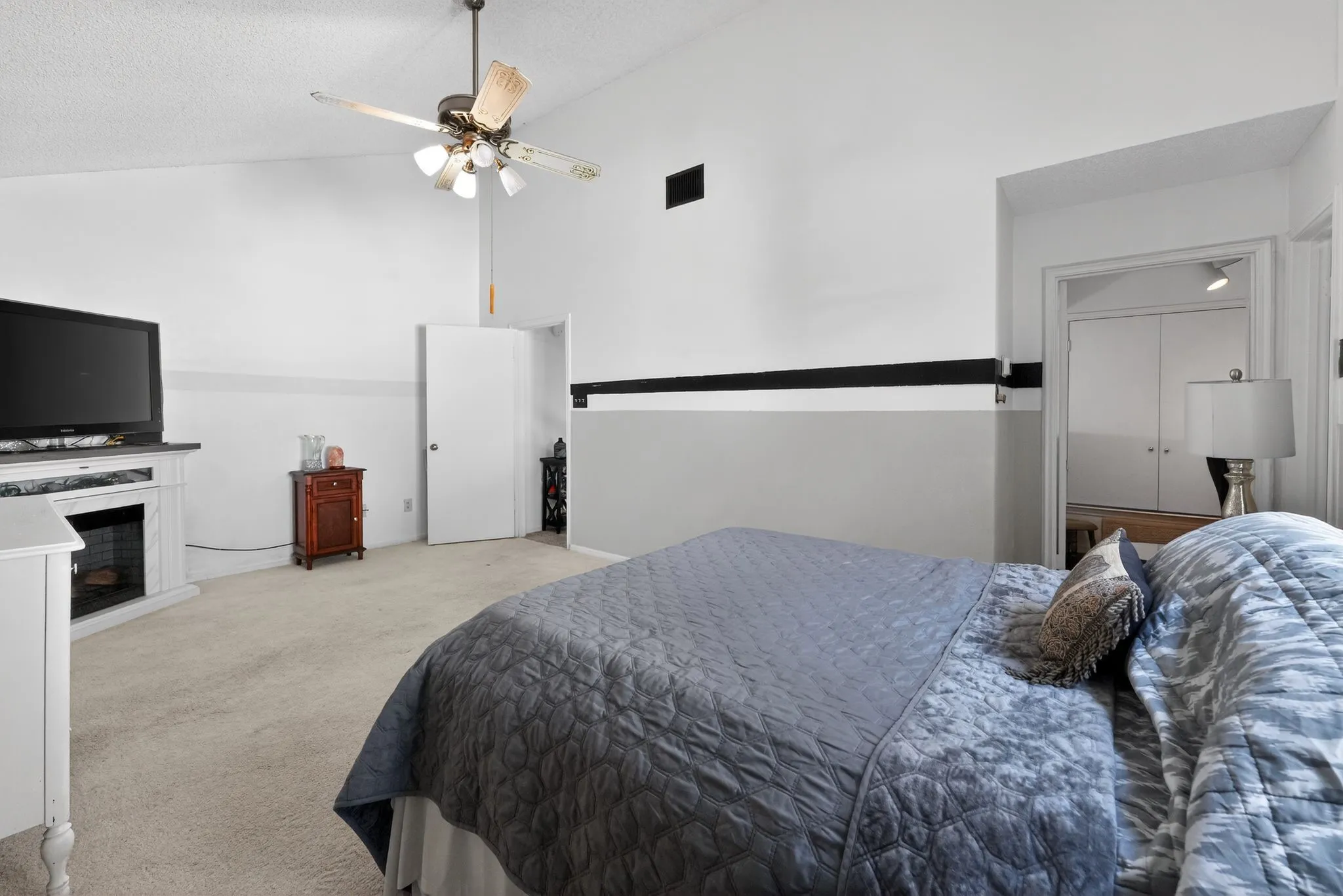 Carpeted bedroom with a vaulted ceiling and ceiling fan