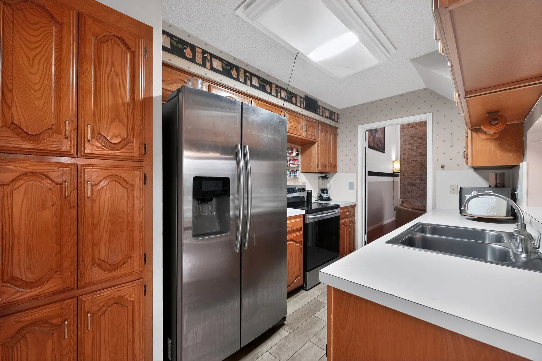 Kitchen featuring wood cabinetry, stainless steel refrigerator, and a double basin sink