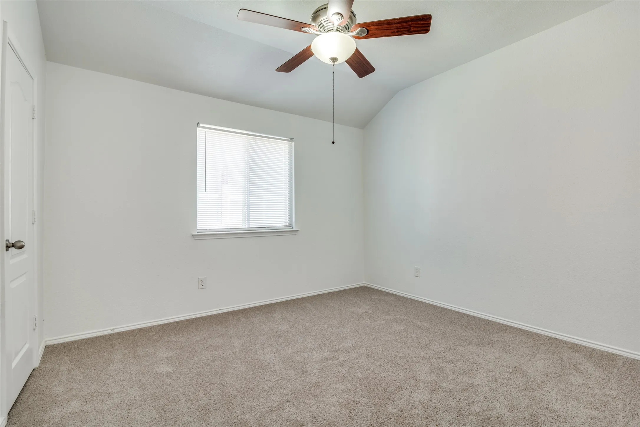 Spare room featuring ceiling fan, lofted ceiling, and light colored carpet