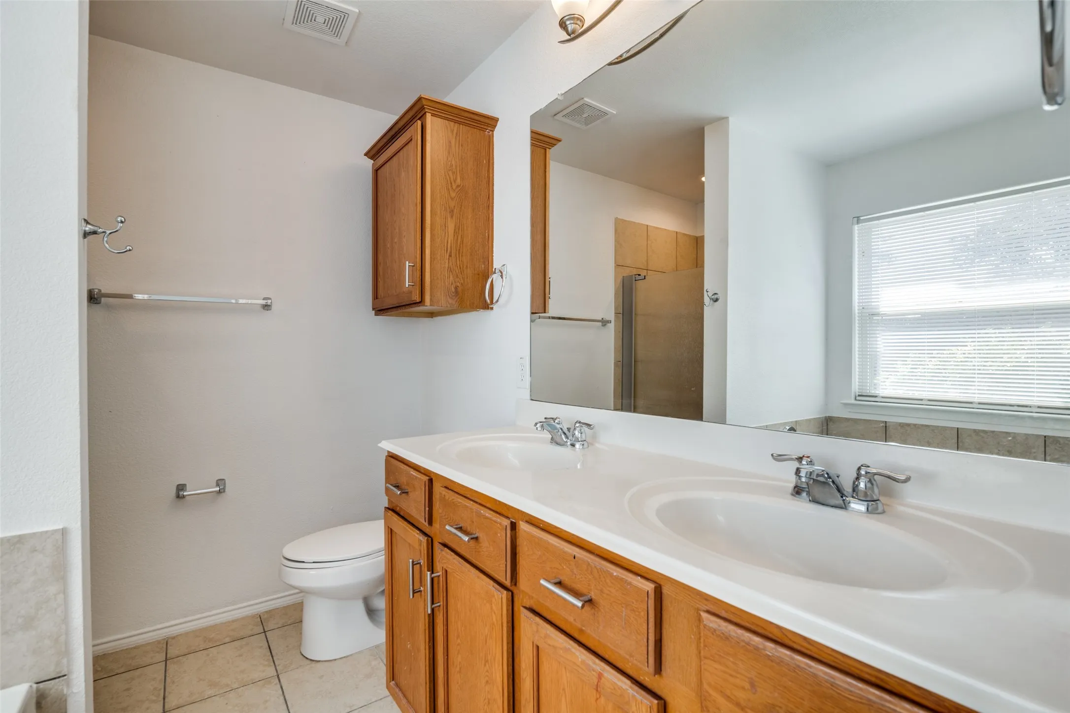 Bathroom with toilet, tile patterned flooring, vanity, and a shower with door