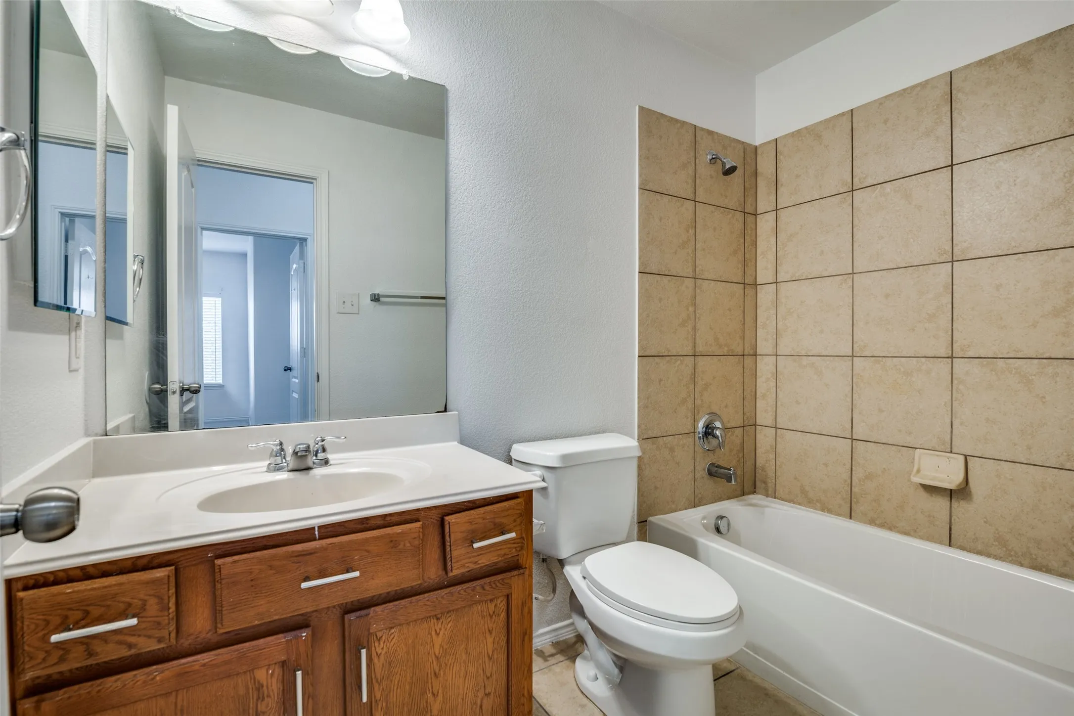 Full bathroom with toilet, tiled shower / bath combo, vanity, and tile patterned floors