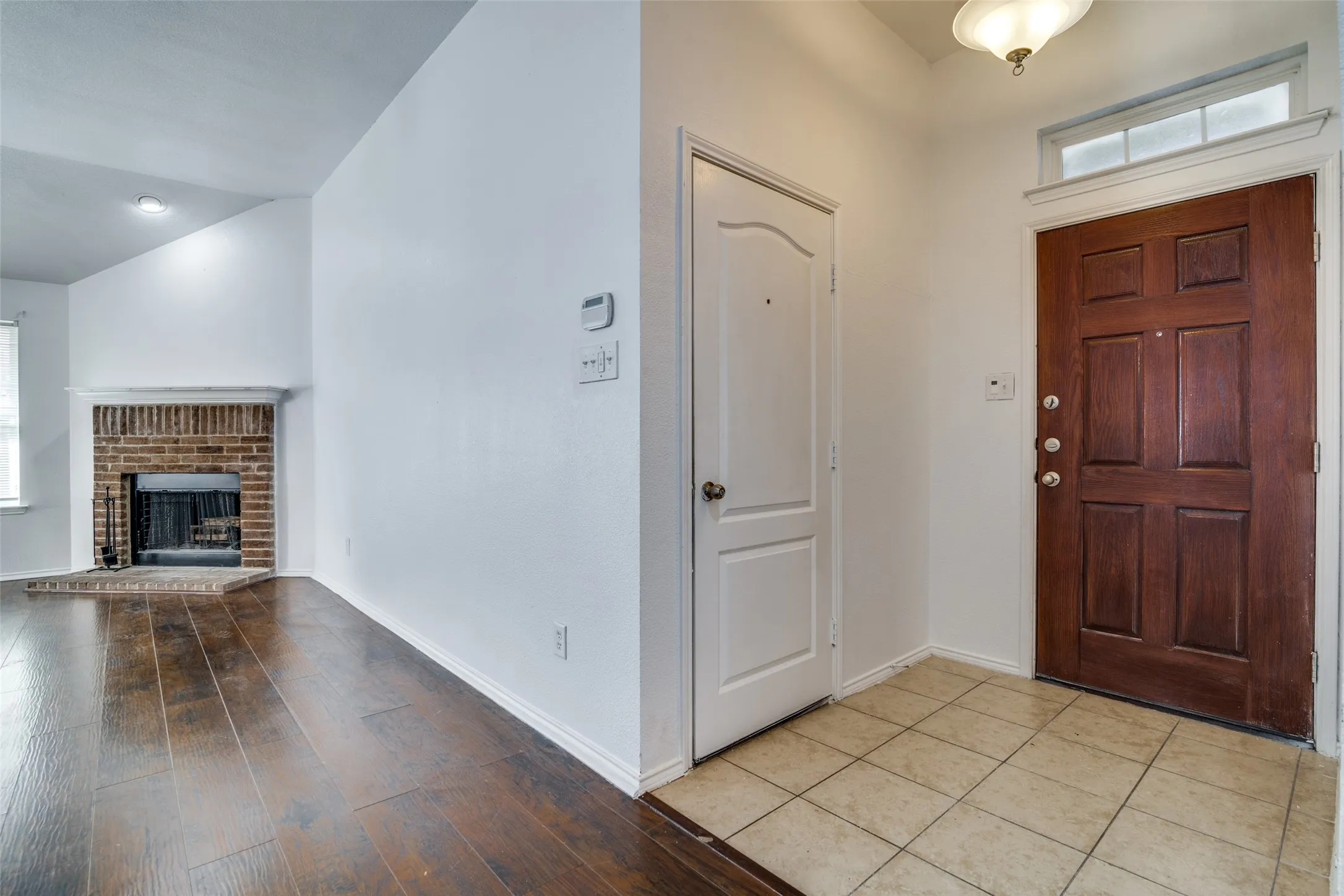 Foyer with light hardwood / wood-style flooring, plenty of natural light, and a brick fireplace