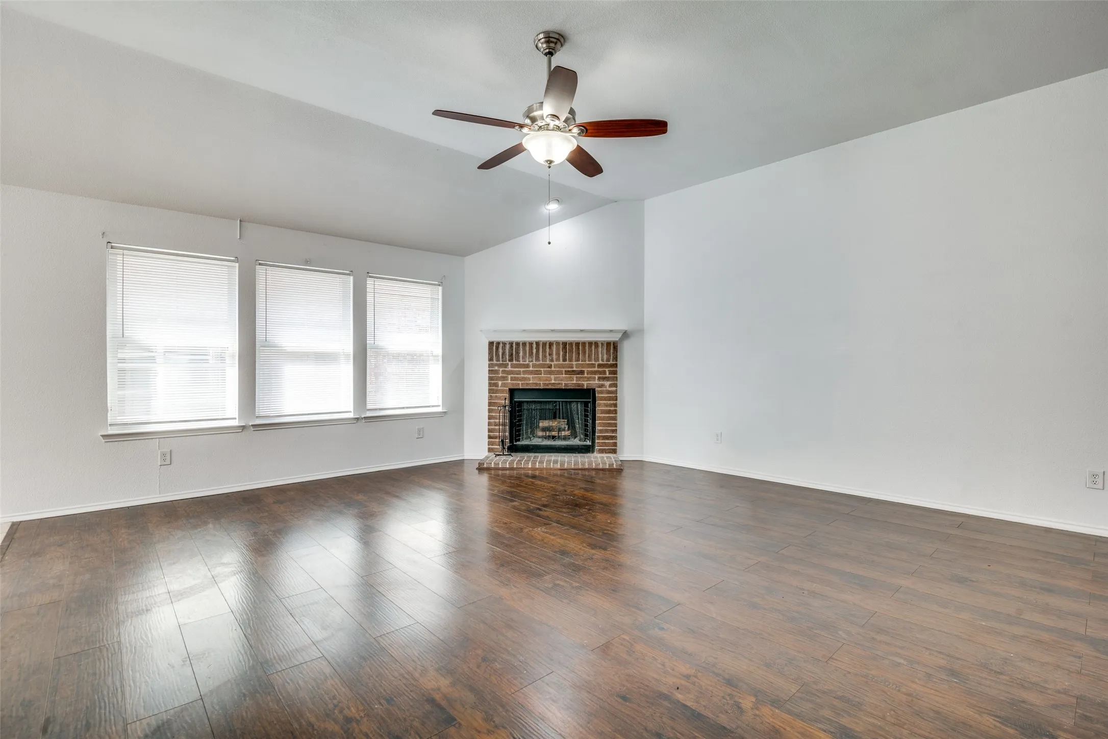 Unfurnished living room featuring dark hardwood / wood-style flooring, ceiling fan, a fireplace, and vaulted ceiling