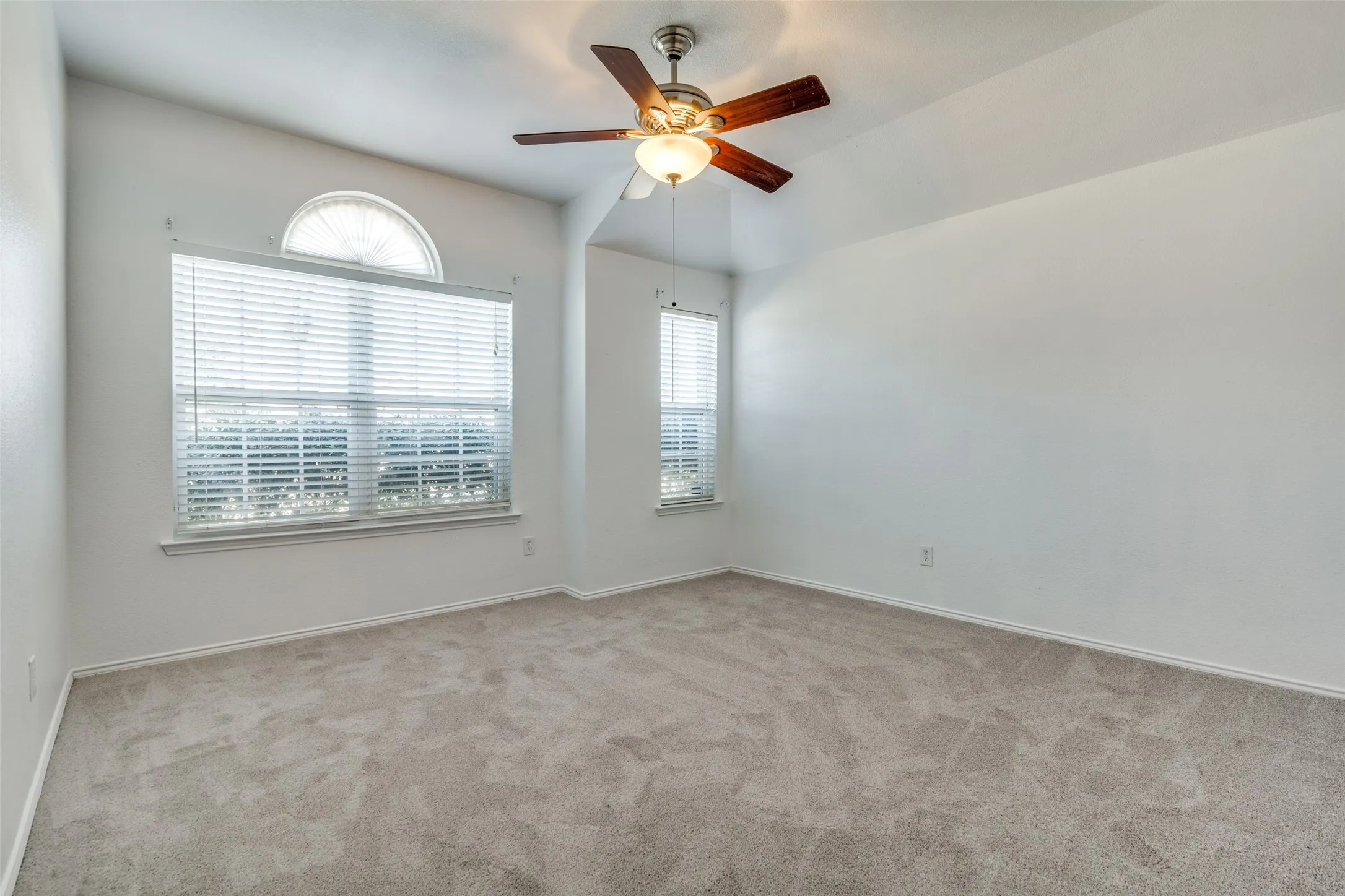 Carpeted spare room with ceiling fan and plenty of natural light