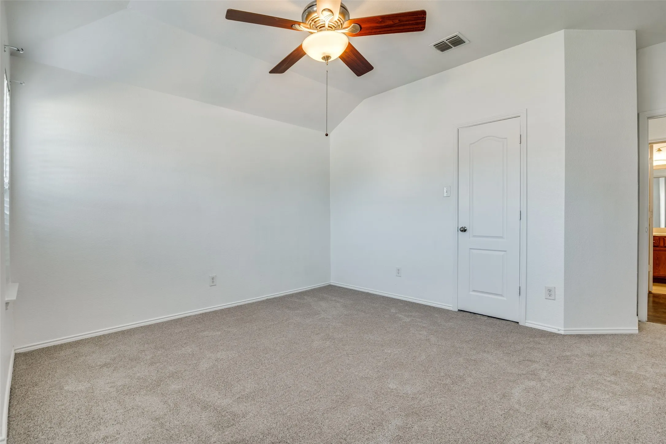 Empty room with light carpet, vaulted ceiling, and ceiling fan