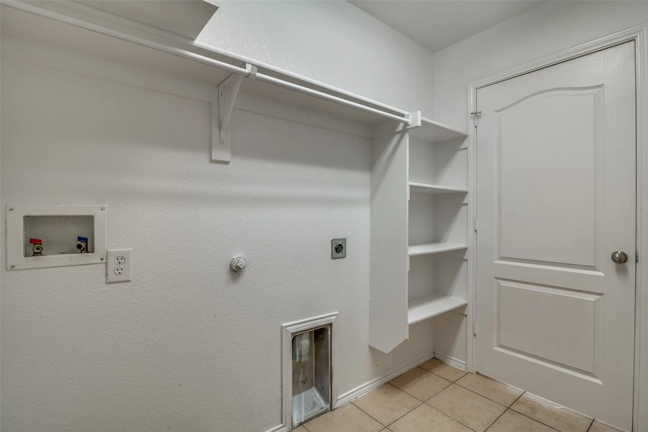 Washroom with hookup for a washing machine, electric dryer hookup, and light tile patterned floors