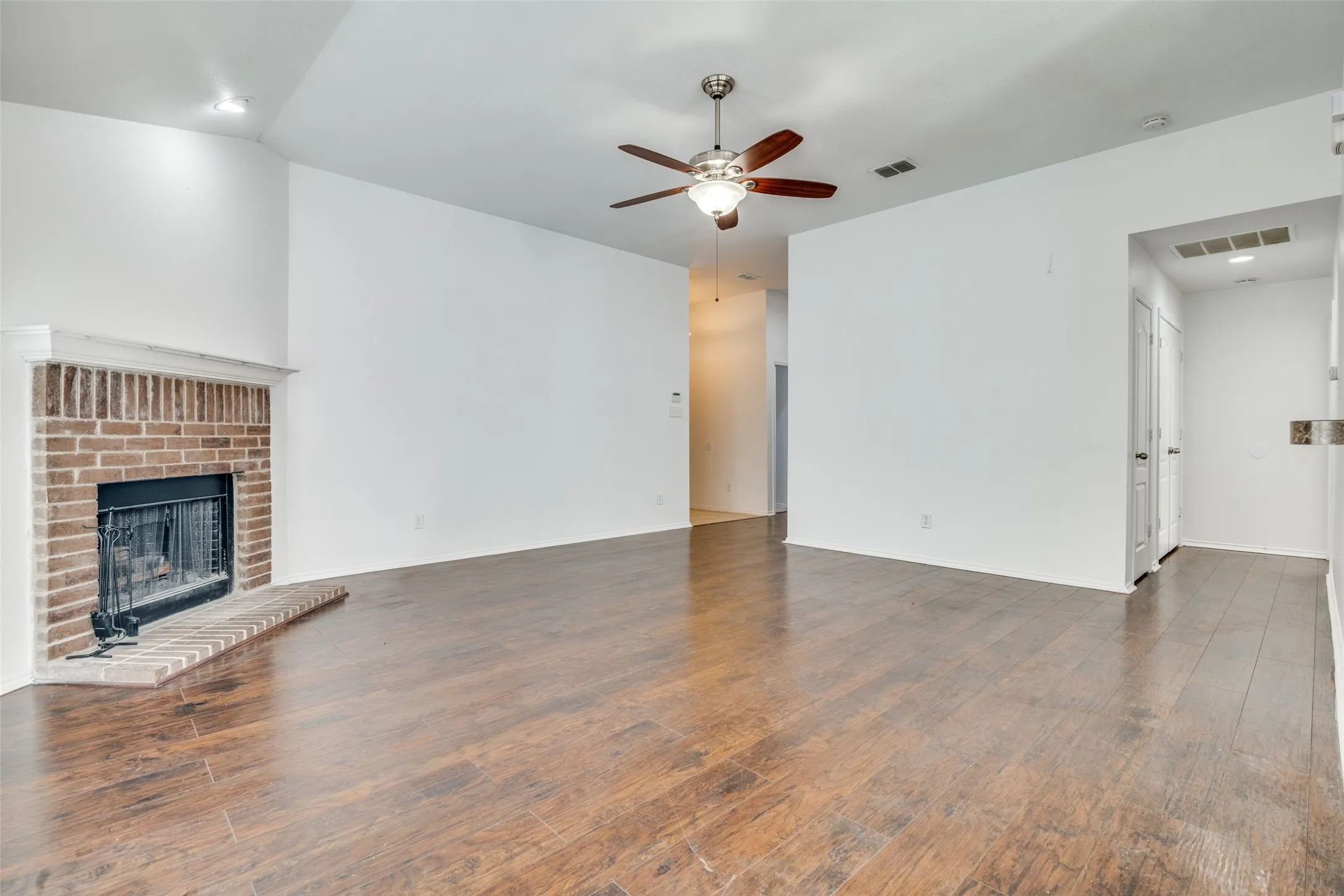 Unfurnished living room with a fireplace, dark hardwood / wood-style floors, and ceiling fan