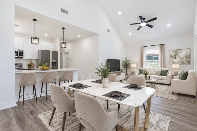 Virtual staging - Open-concept living space featuring wood-finish flooring, a vaulted ceiling, and recessed lighting