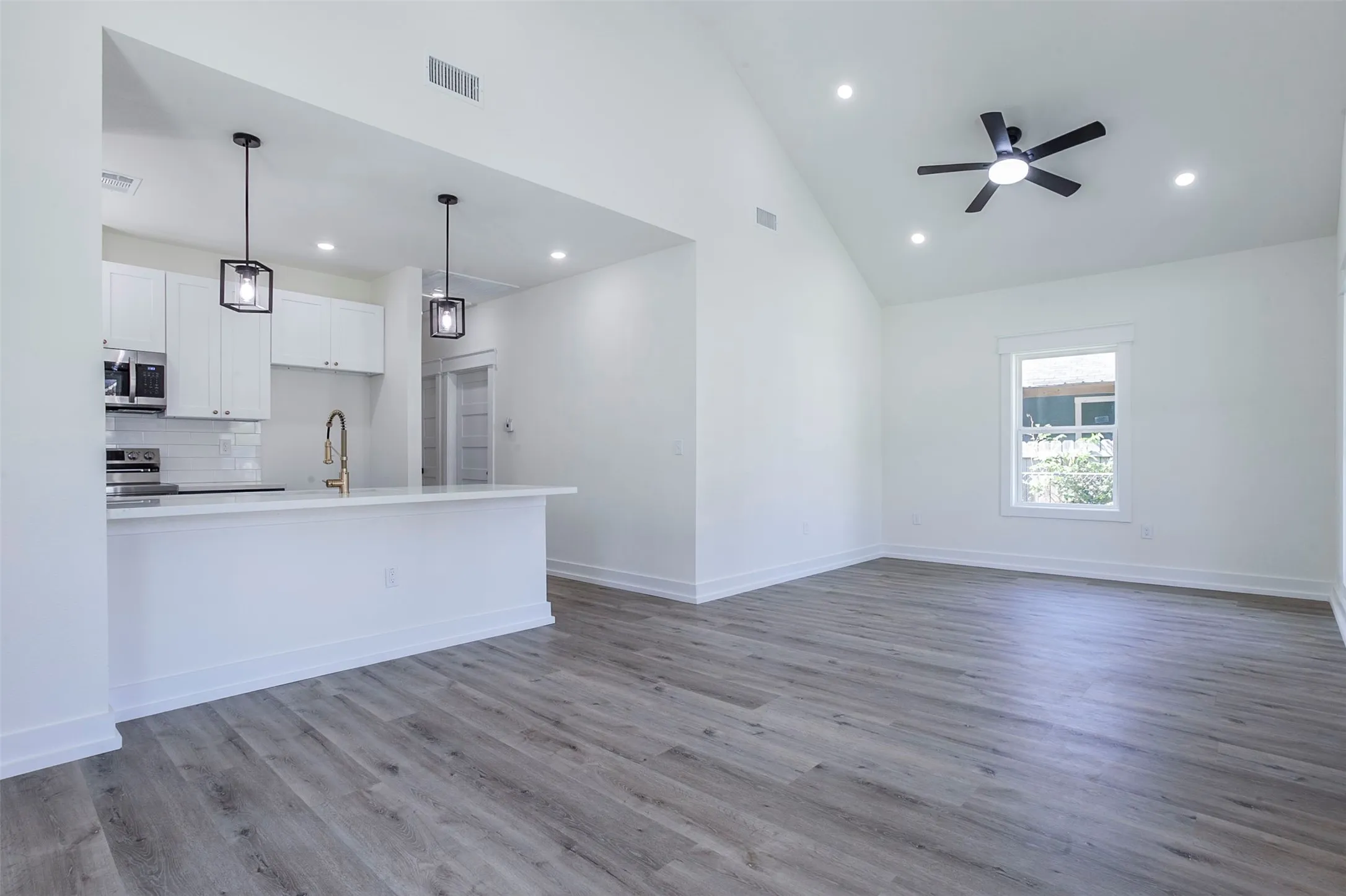 Open-concept living space featuring wood-finish flooring, a vaulted ceiling, and recessed lighting
