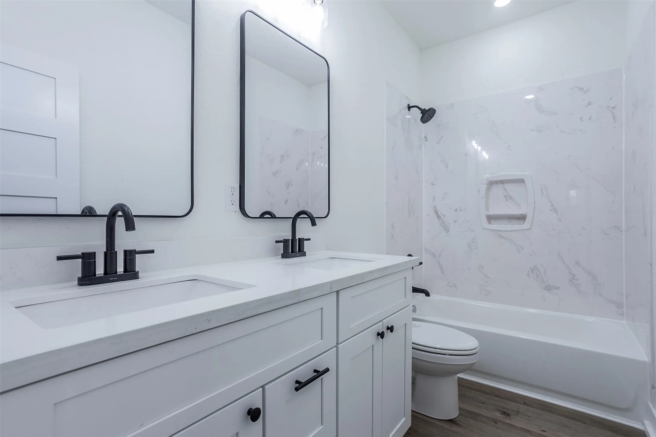 Bathroom featuring a double vanity with matte black fixtures, integrated sinks, white countertops, and shaker-style cabinetry