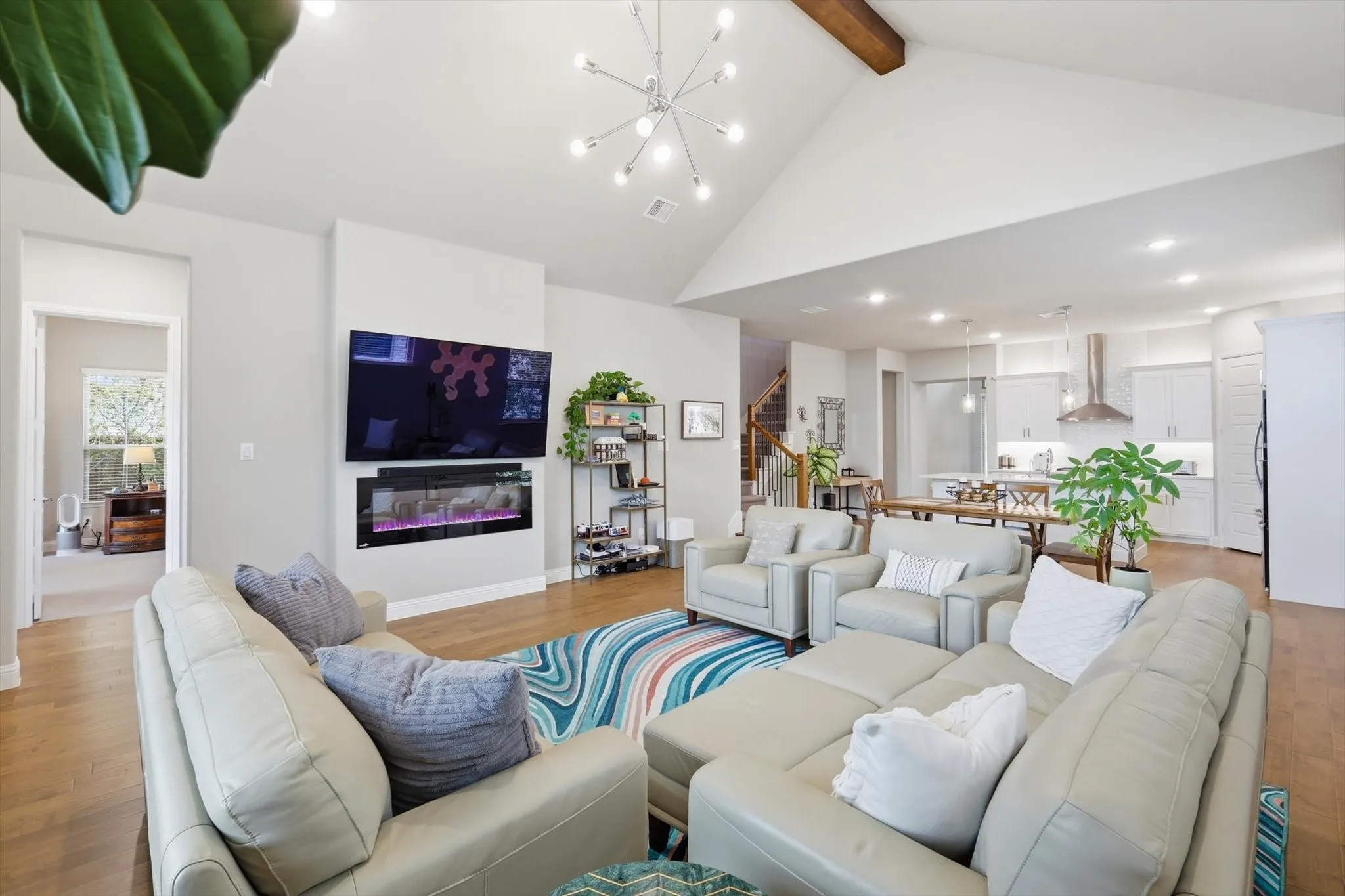 Expansive family room features vaulted ceilings with a custom cedar beam, & a designer fireplace.
