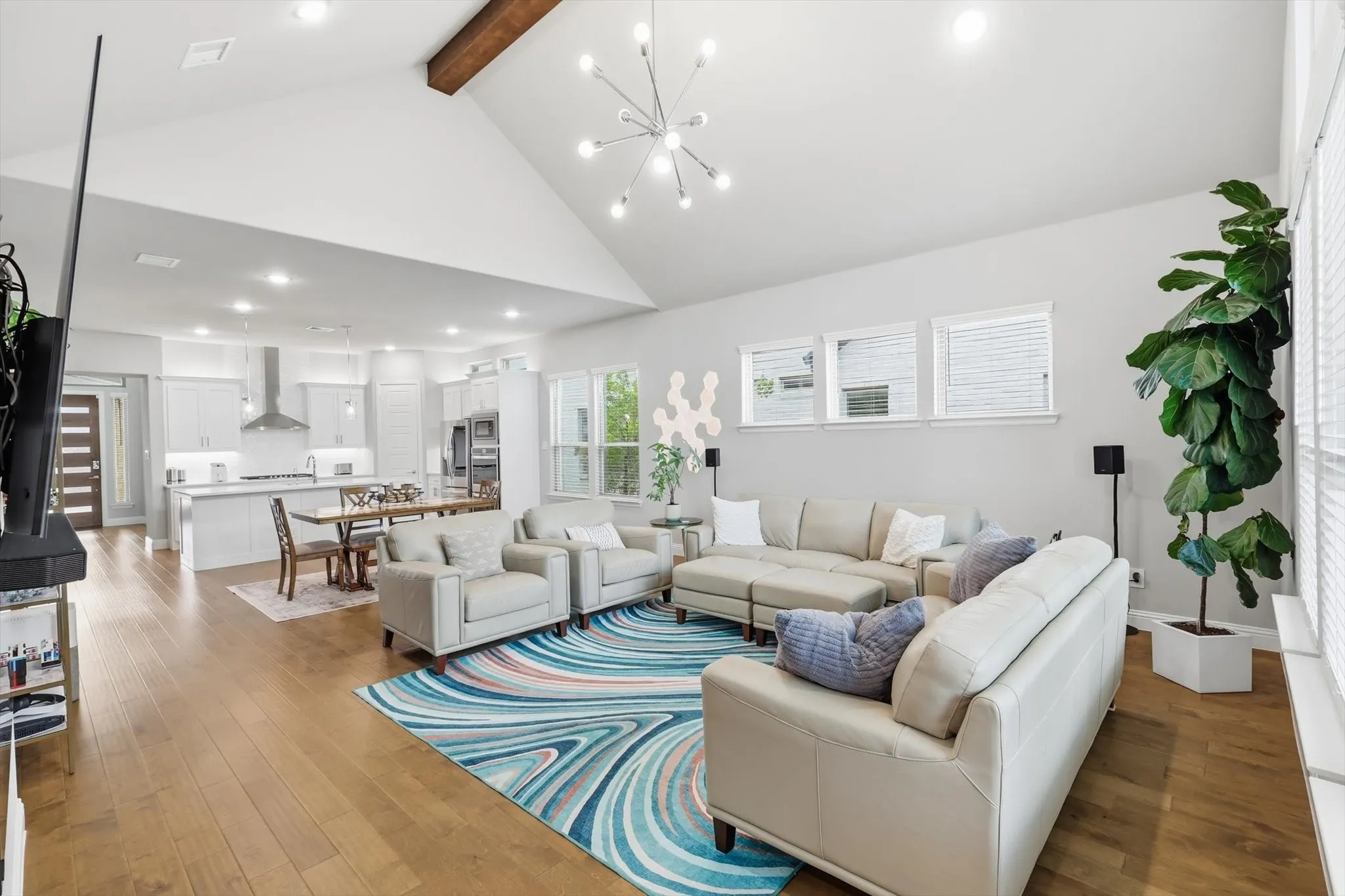 Expansive family room features vaulted ceilings with a custom wood beam & a designer fireplace.
