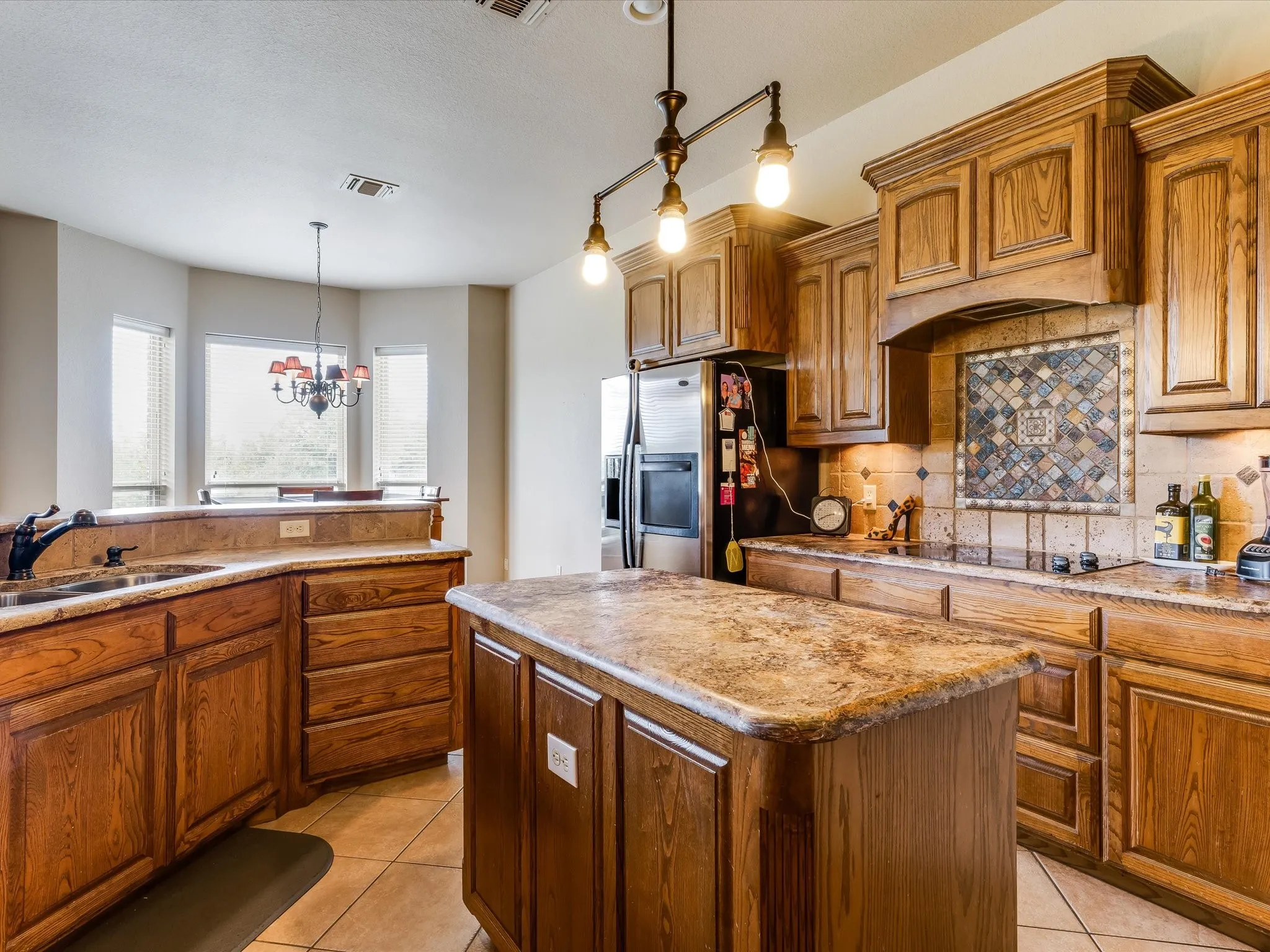 Kitchen featuring wood cabinetry, a central island with a solid surface countertop, and tile flooring