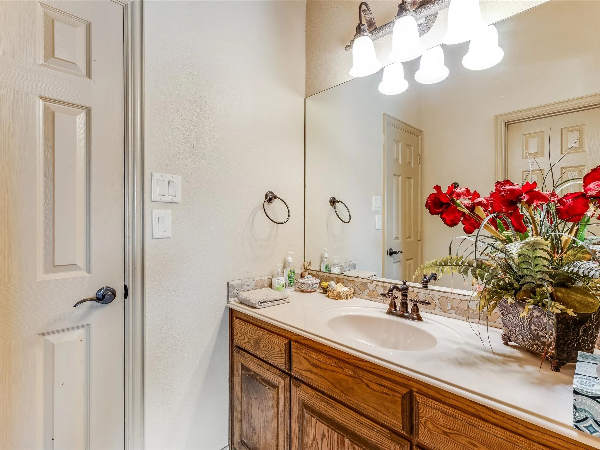 Bathroom vanity with wood-finish cabinetry, a light-toned countertop, and a built-in sink