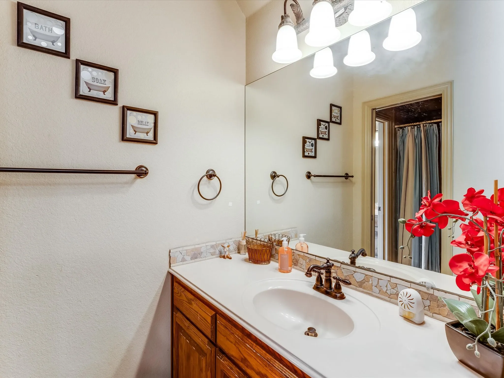 Vanity area featuring a built-in sink, dark bronze-finish fixtures, a light-toned countertop, and wood-finish cabinetry
