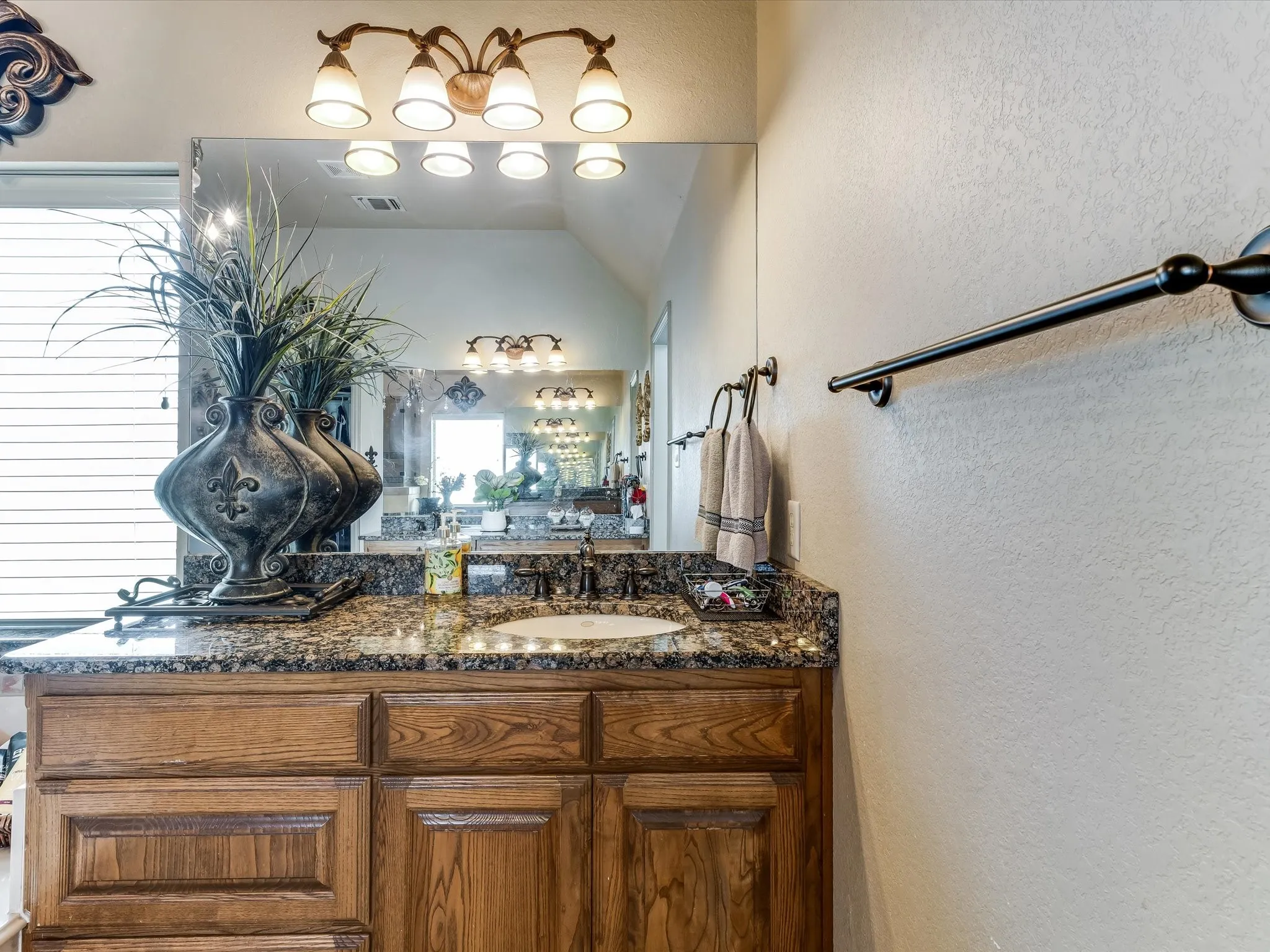 Vanity featuring a built-in sink, dark countertop, wood cabinetry, and a large wall-mounted mirror