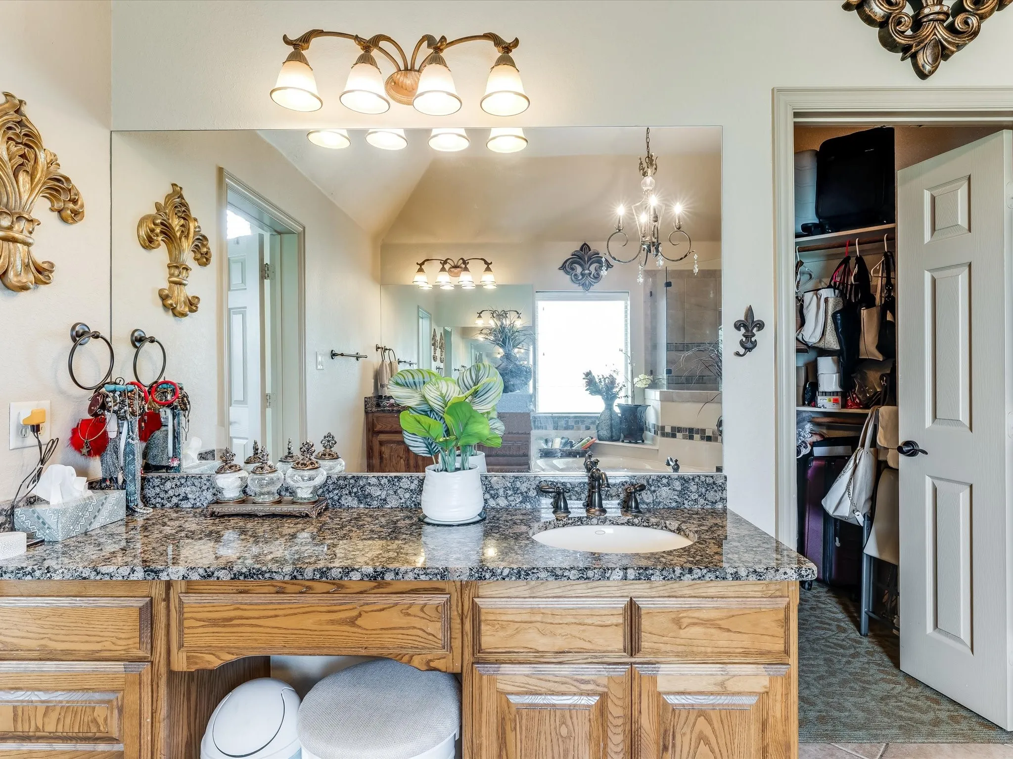 Double vanity featuring granite countertops, wood-finish cabinetry, an undermount sink, and a large wall-mounted mirror