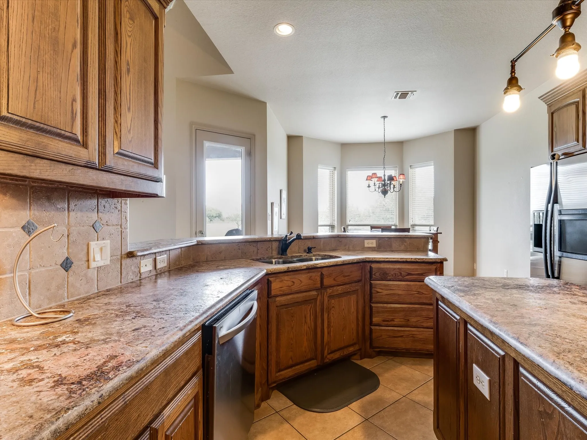 Kitchen featuring wood cabinetry, stone-finish countertops, and a tile backsplash with decorative accents