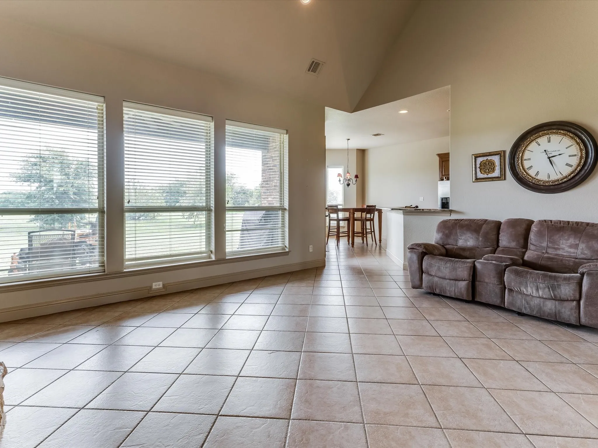 Spacious living area featuring large windows with horizontal blinds, providing ample natural light