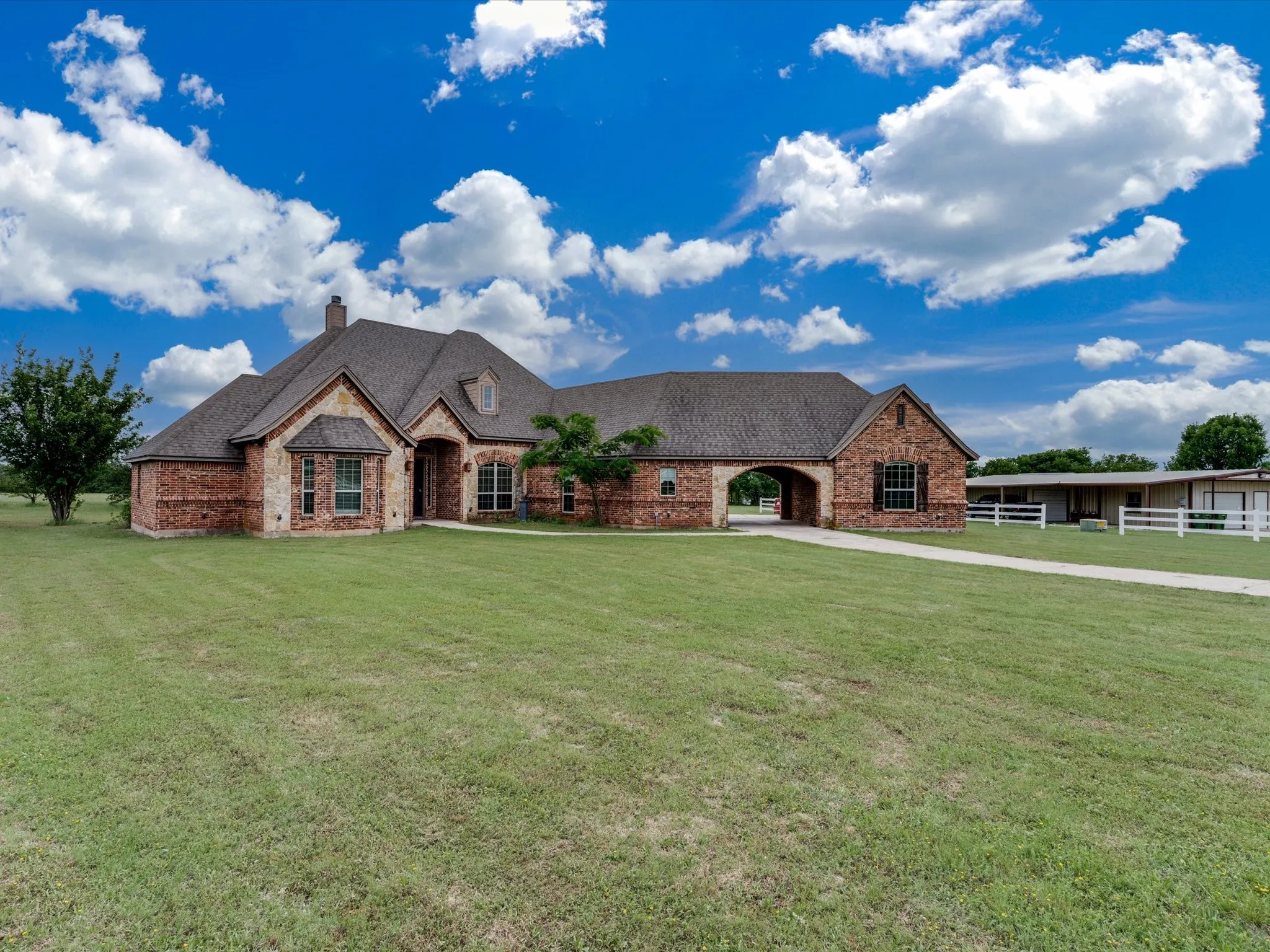Brick and stone exterior with a dark shingle roof