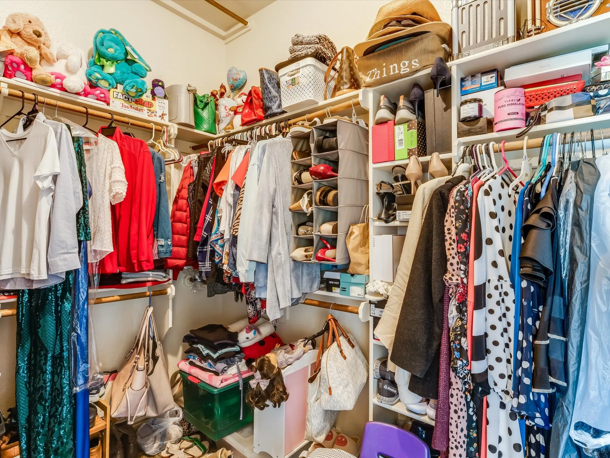 Spacious walk-in closet featuring multiple shelving units, varied hanging rods, built-in shoe storage, and overhead storage options